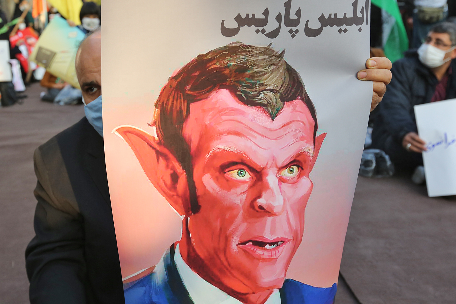 Demonstran membawa gambar kartun Presiden Prancis Emmanuel Macron dalam aksi demonstrasi di depan Kedubes Prancis di Teheran, Iran.