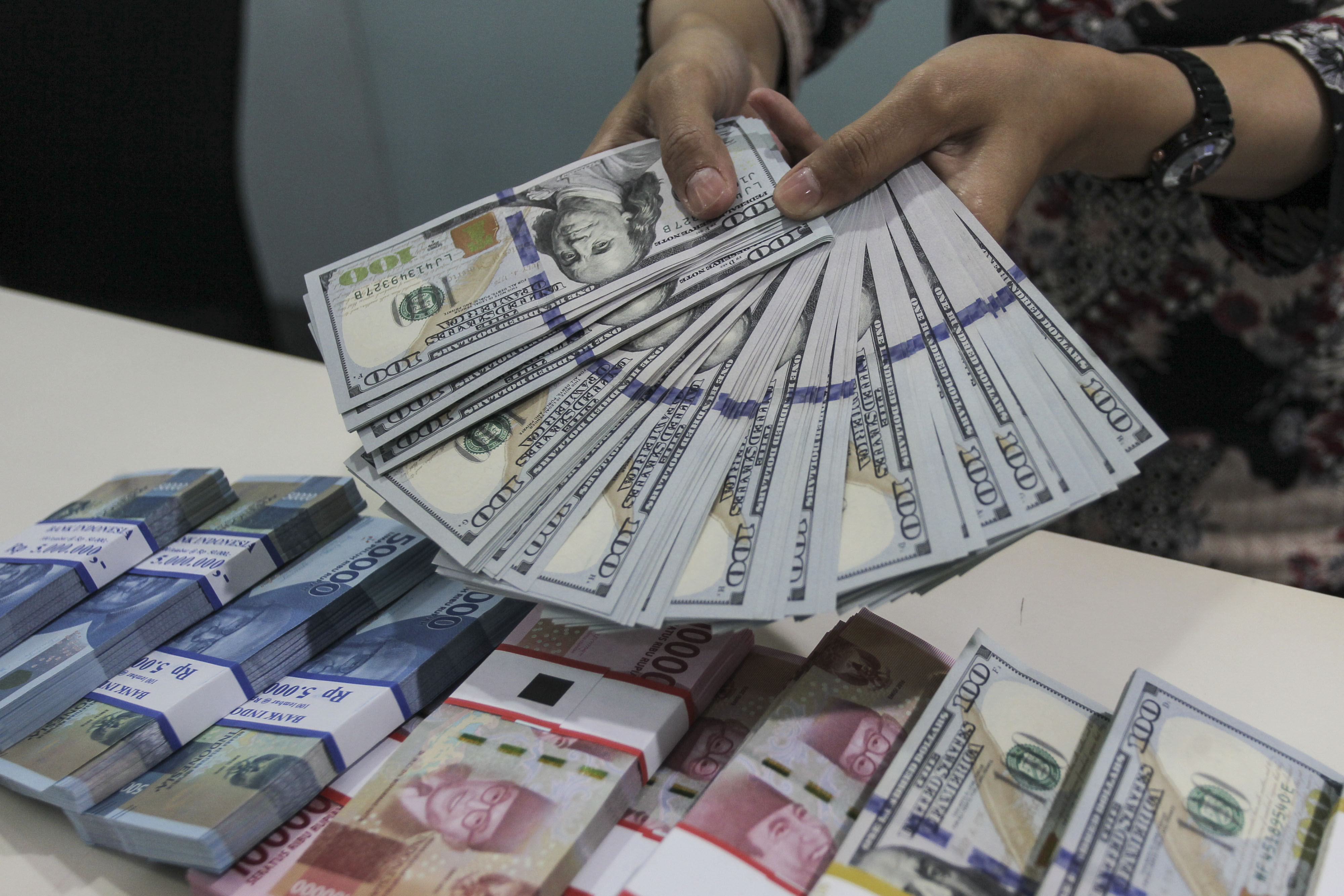 Karyawan menunjukkan uang rupiah dan dolar AS di Kantor Cabang Plaza Mandiri, Jakarta.