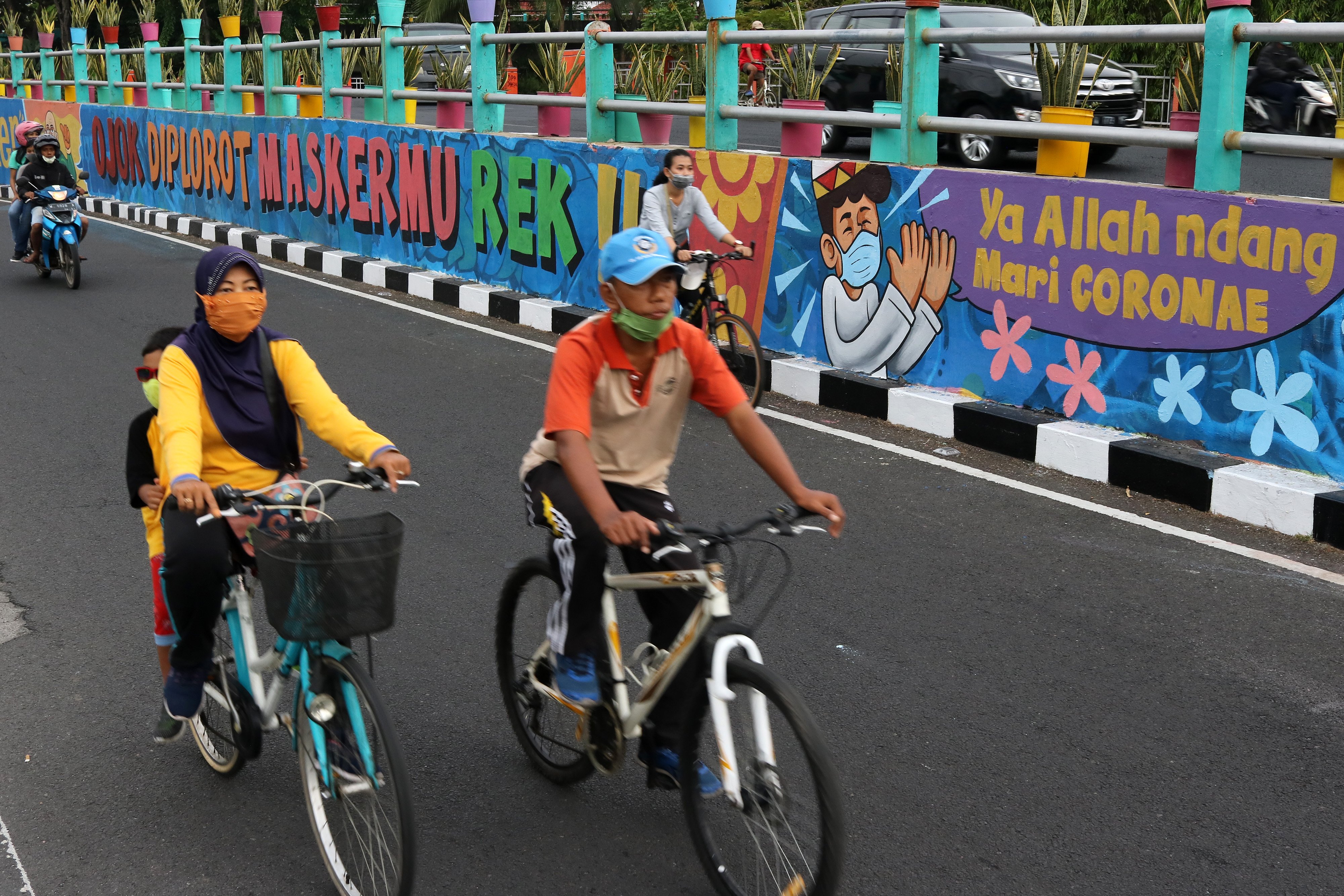 Sejumlah pesepeda melintas di dekat dinding bermural di Surabaya, Jawa Timur, Minggu (18/10/2020).