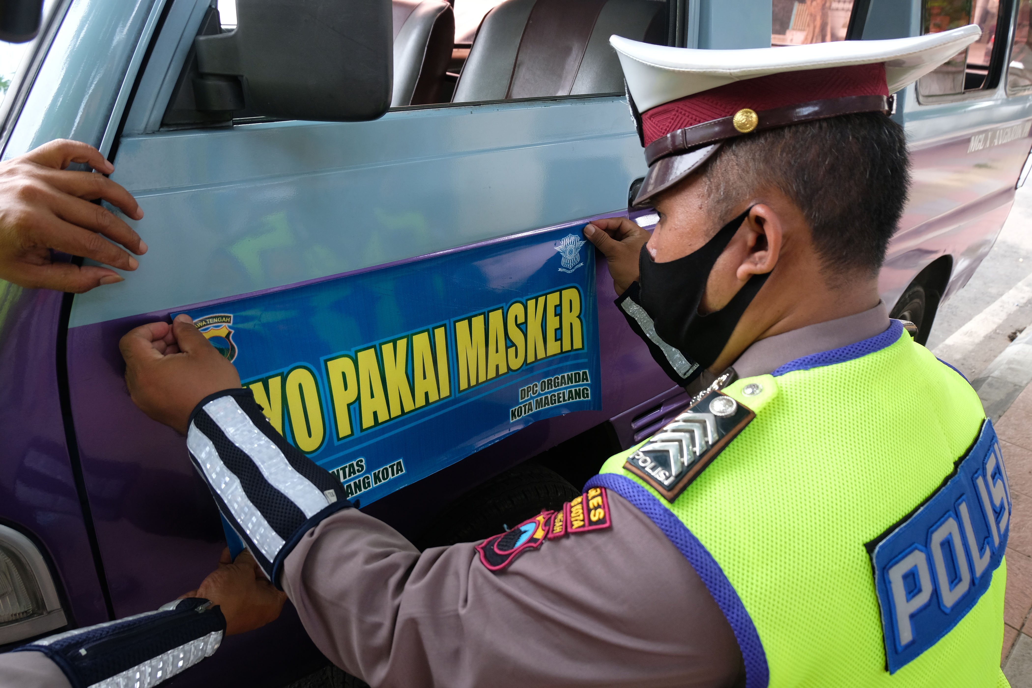 Polisi memasang stiker imbauan memakai masker pada kendaraan angkutan umum di kota Magelang, Jawa Tengah, Jumat (9/10/2020)