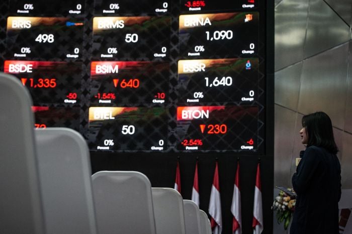 Karyawan beraktivitas di dekat grafik pergerakan saham di gedung Bursa Efek Indonesia, Jakarta. 