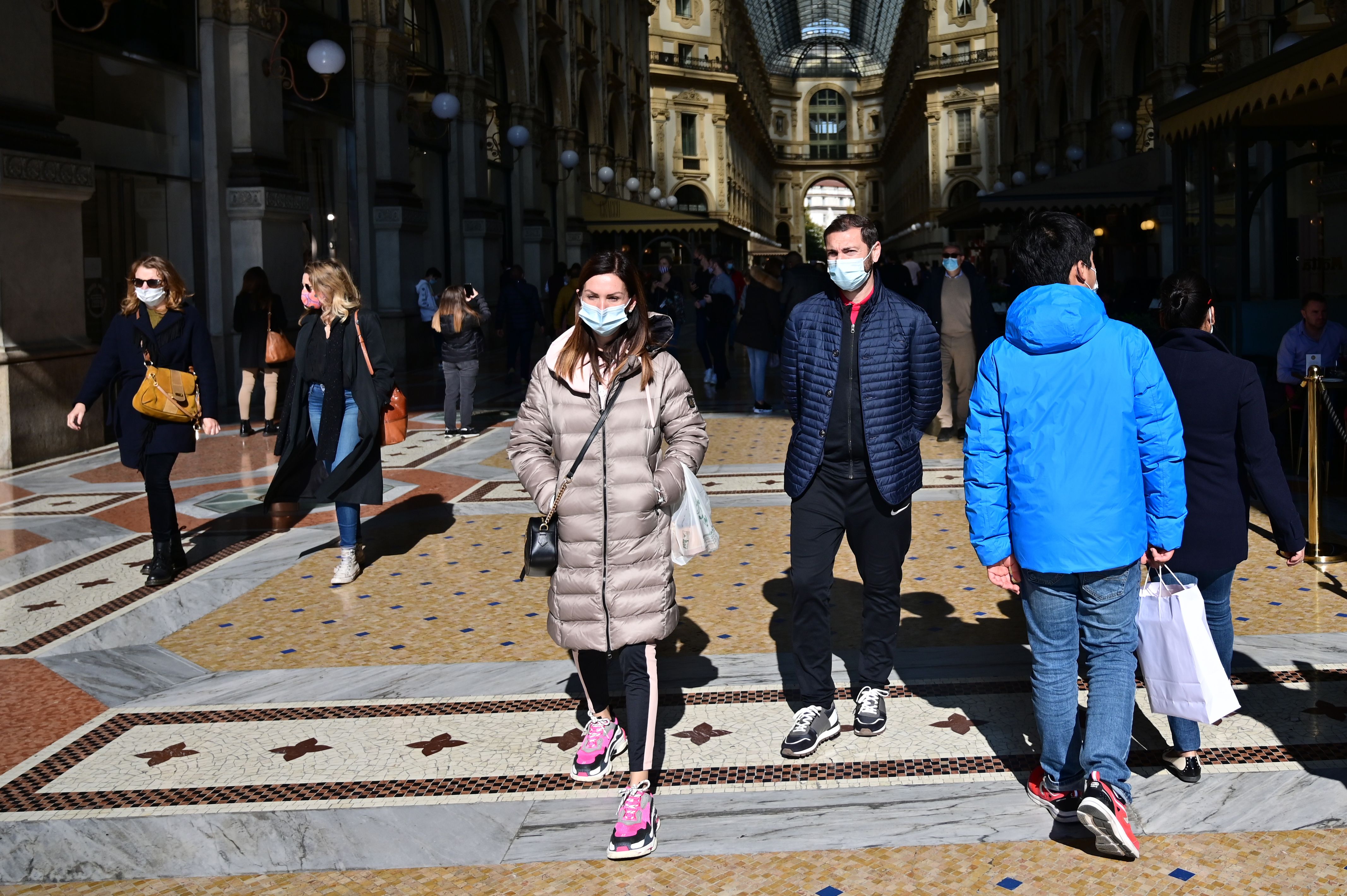 Warga mengenakan masker saat berjalan-jalan di Kota Milan, Italia.
