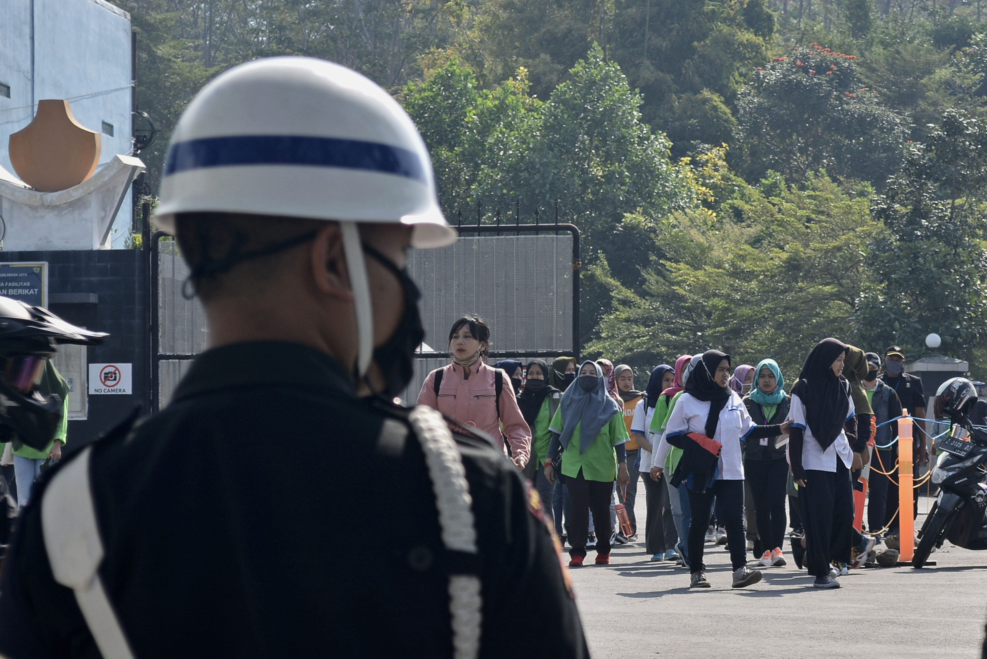 Tenaga kerja di sebuah pabrik berangsur keluar area kerja usai jam kerja 