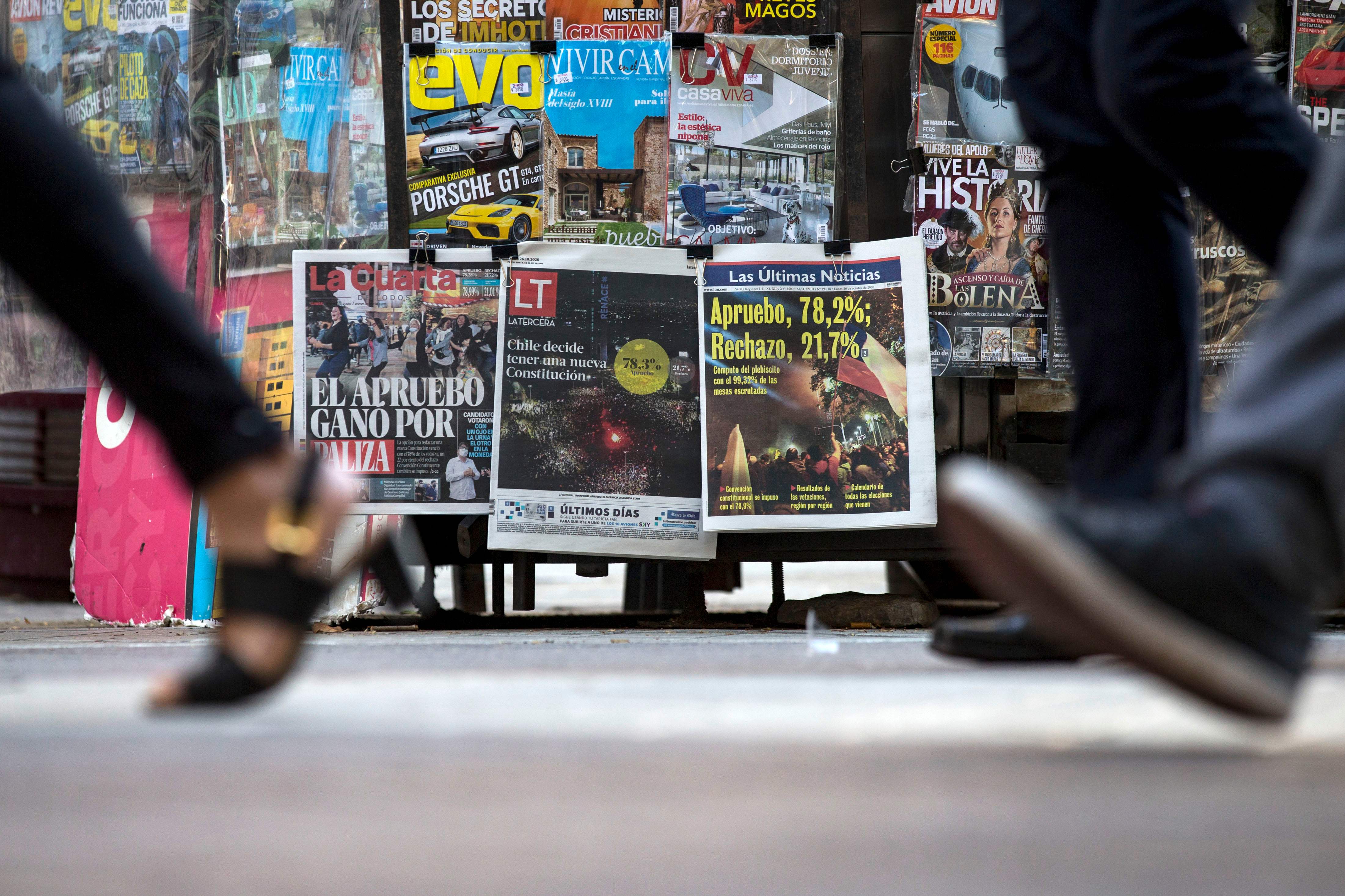 Warga melintas di depan kios koran di Santiago, Cile, sehari selepas referendum yang mengantarkan warga Cile mengganti konstitusi.