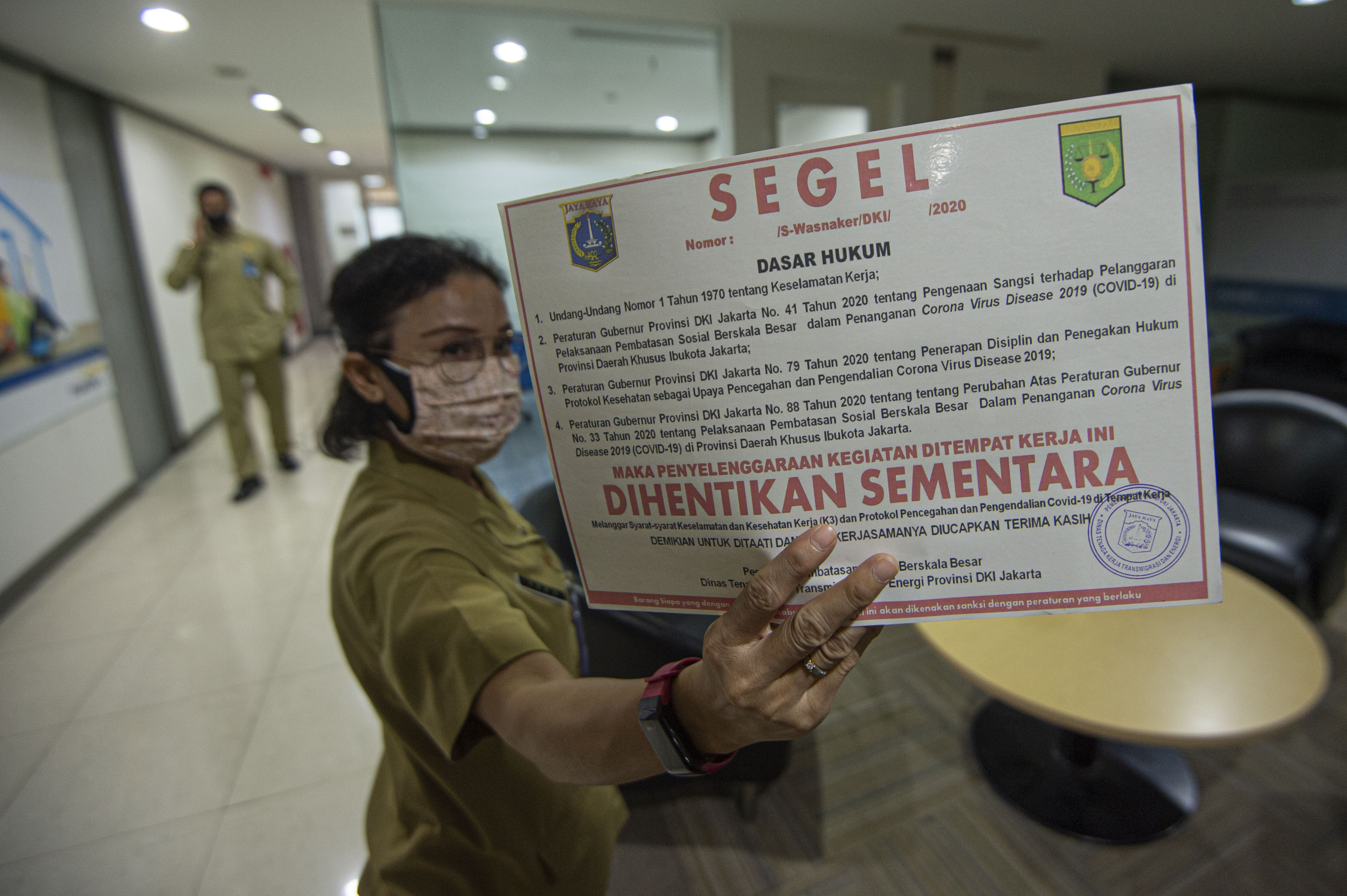 Petugas dari Pemerintah Provinsi (Pemprov) DKI Jakarta menunjukkan stiker segel yang akan dipasang pada perkantoran yang beroperasi.