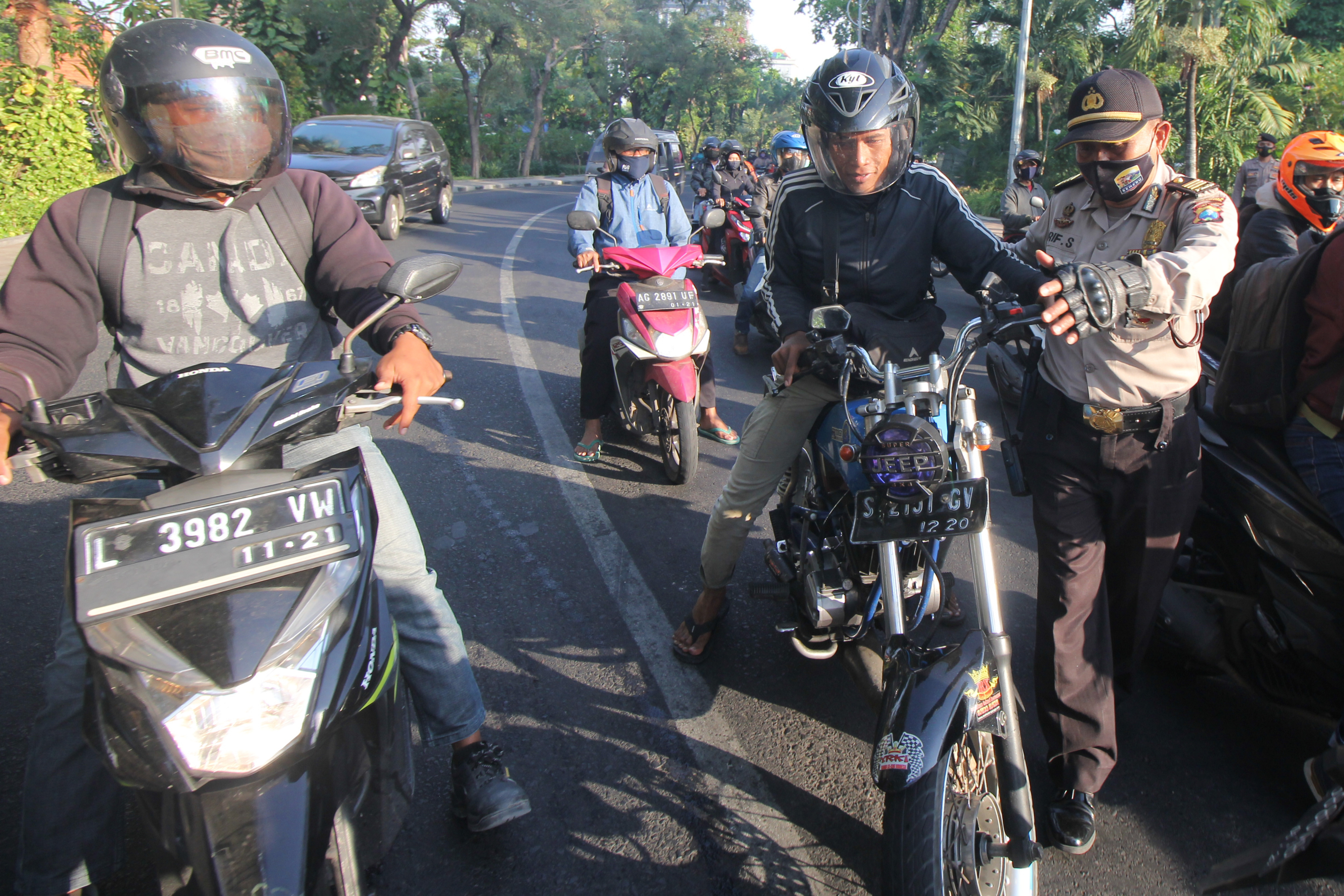 Polisi menghentikan seorang pengendara yang tidak menggunakan masker saat Operasi Yustisi Penegakan Disiplin Protokol Kesehatan di Surabaya.