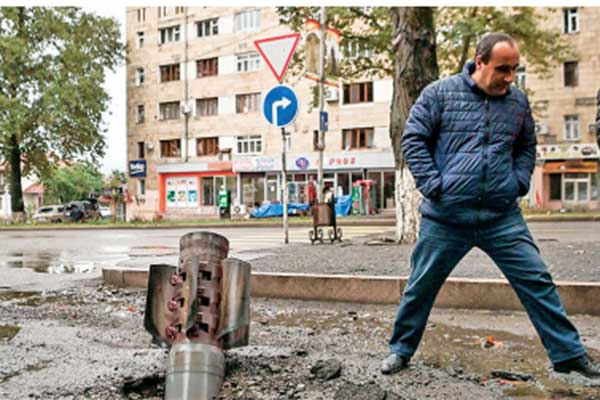 Seorang warga melewati roket yang tidak meledak di kota utama Stepanakert di wilayah Nagorno-Karabakh, kemarin