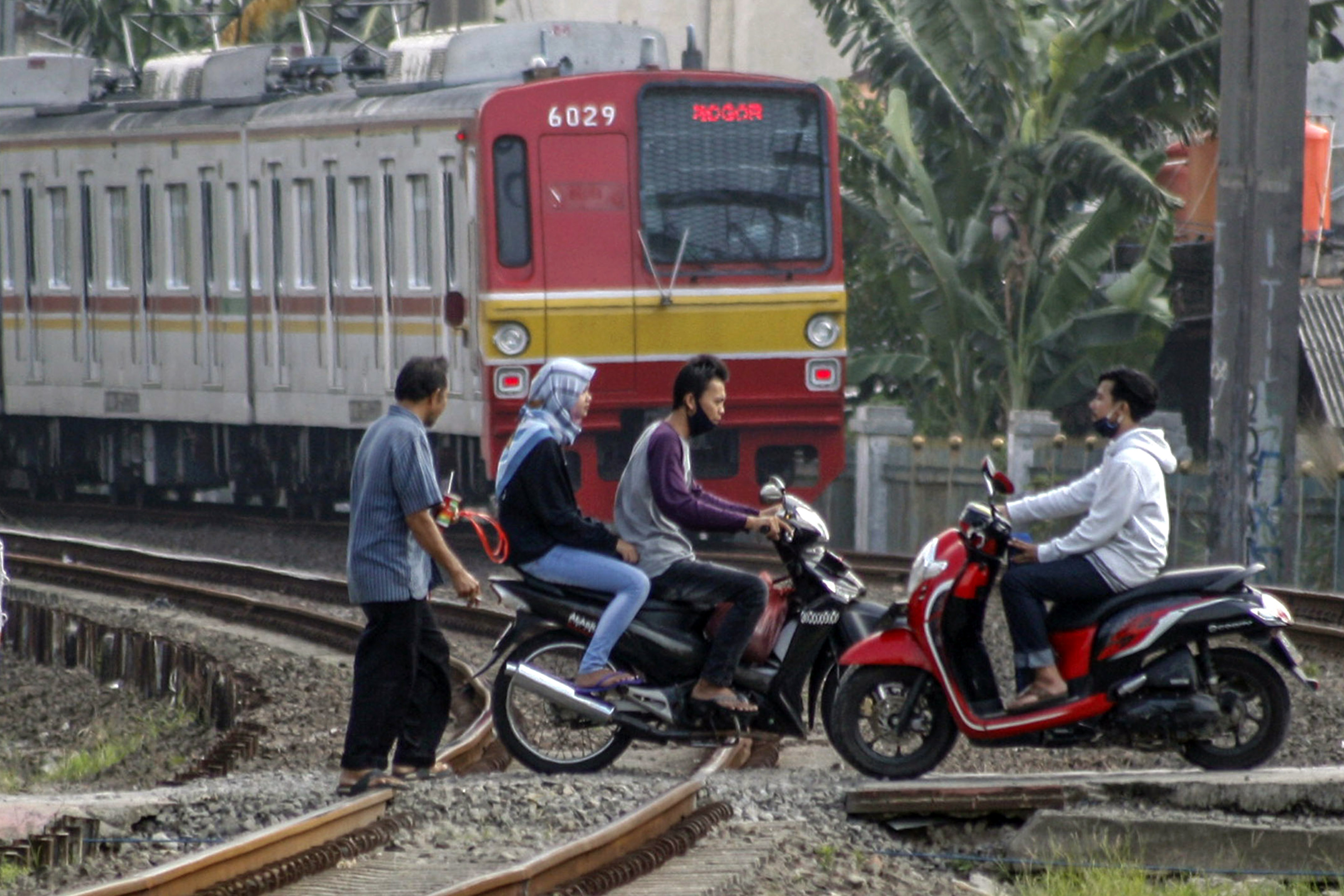Pengendara motor melintas di perlintasan sebidang kereta tanpa palang pintu di Bojong Gede, Bogor.