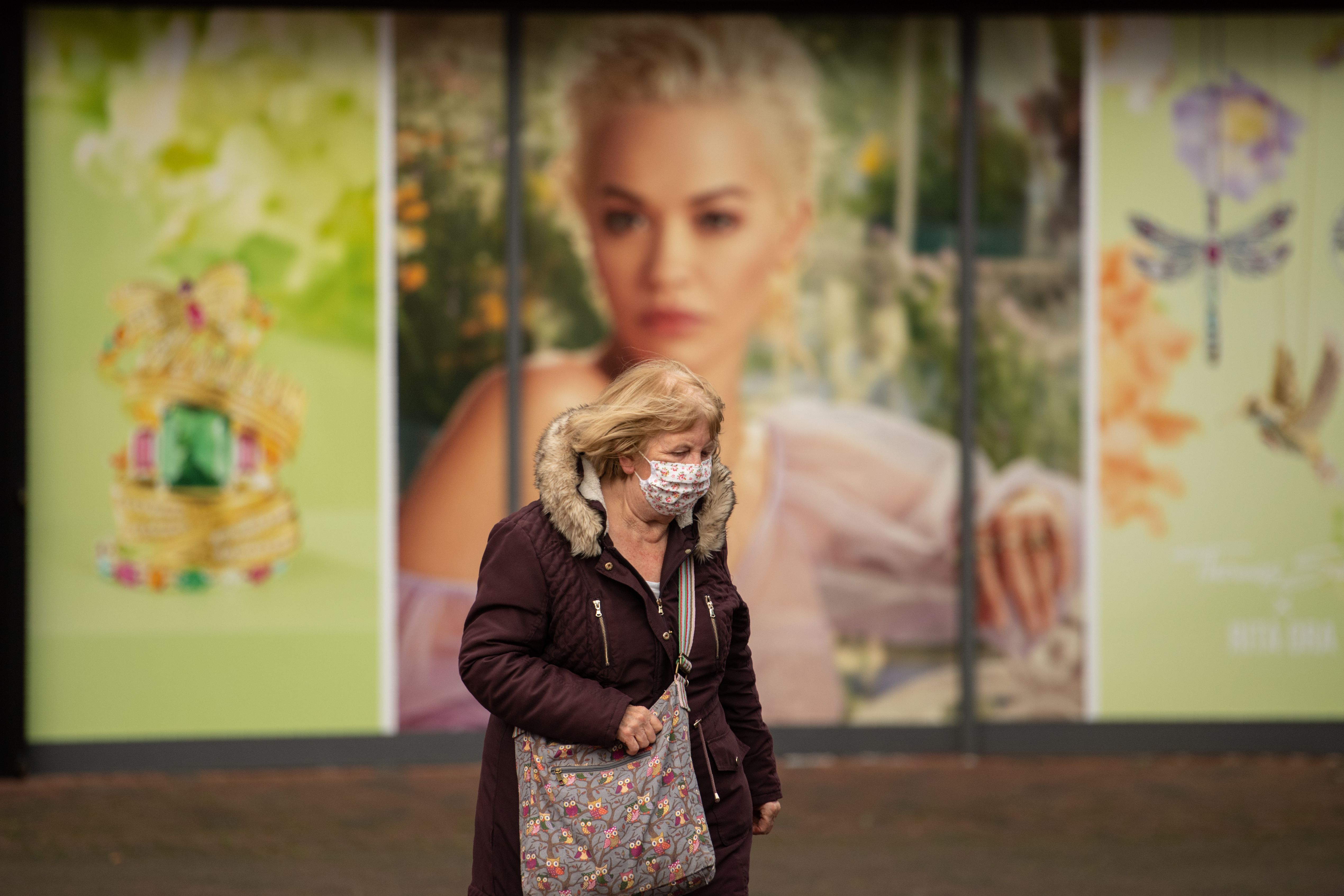 Warga mengenakan masker berjalan di Leigh, Greater Manchester, Inggris.