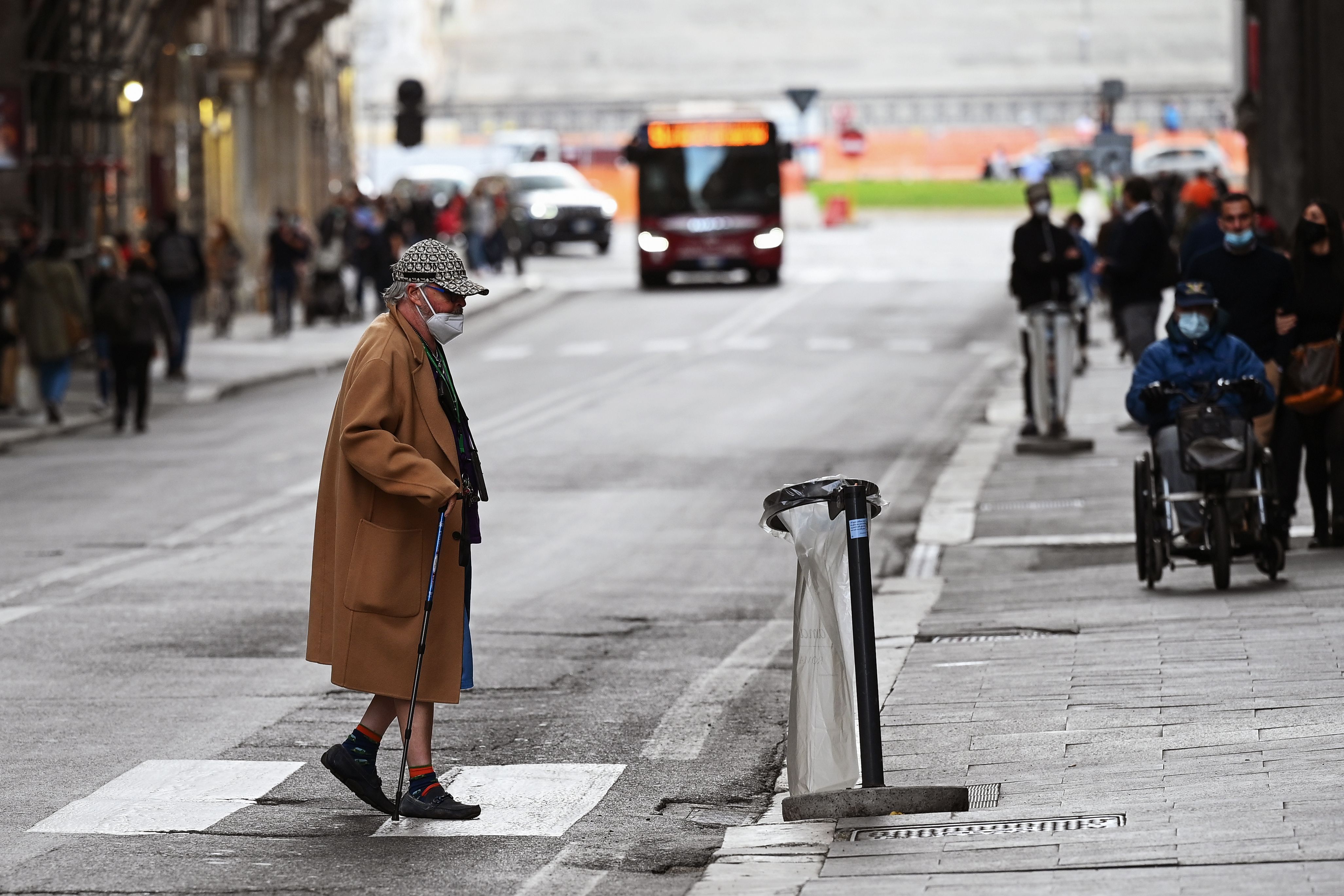 Seorang perempuan mengenakan masker menyeberang jalan di Roma, Italia.