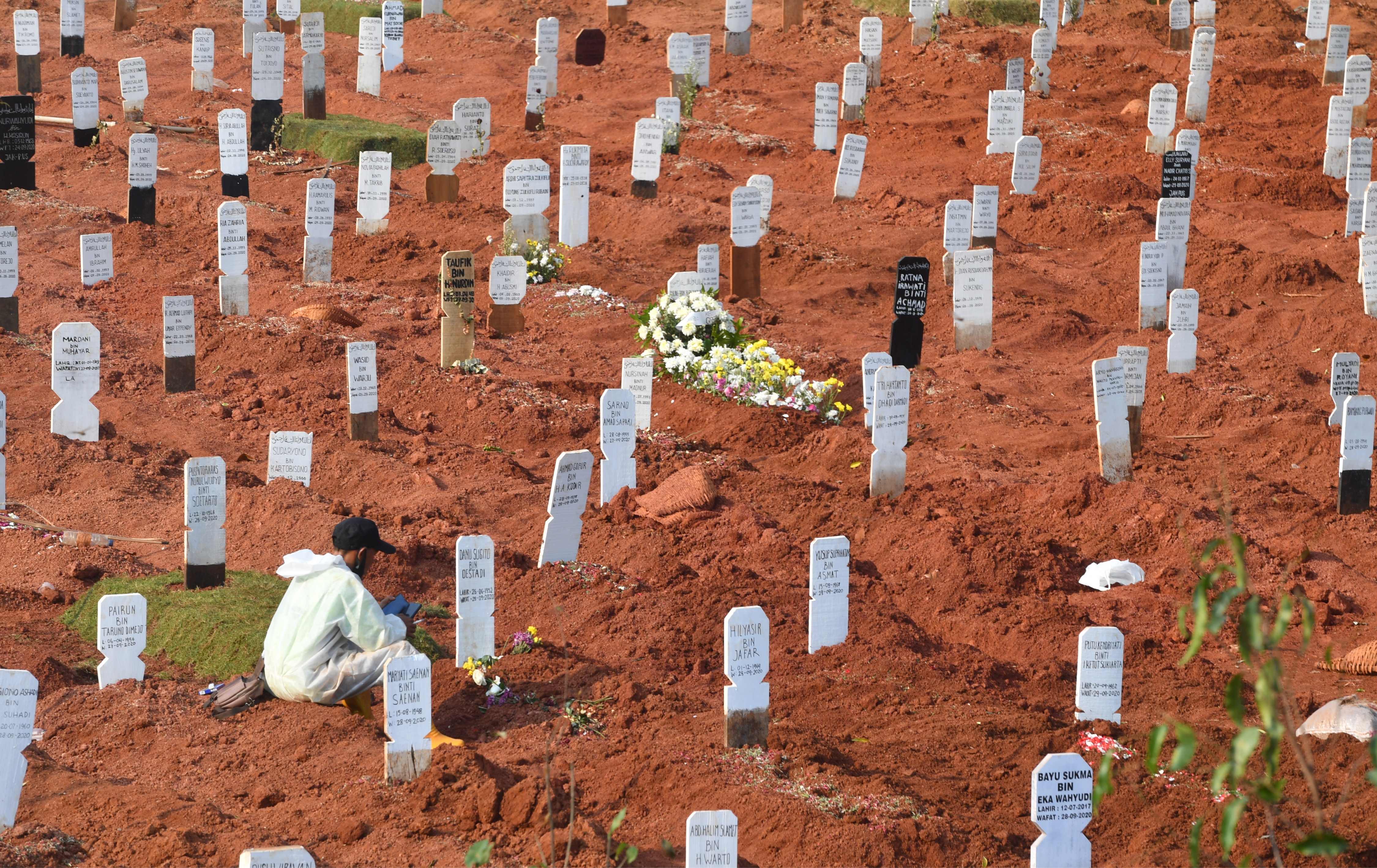 Seorang petugas pemakaman beristirahat di TPU Pondon Ranggon, Jakarta.