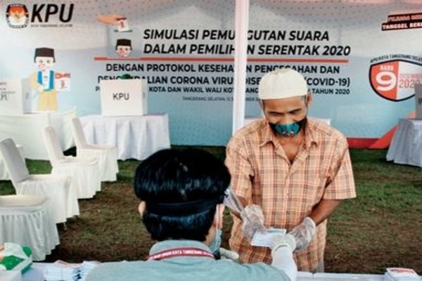 Simulasi -- Petugas memberikan surat suara kepada pemilih yang memakai masker dan sarung tangan, Serpong, Tangerang Selatan, Sabtu (12/9).
