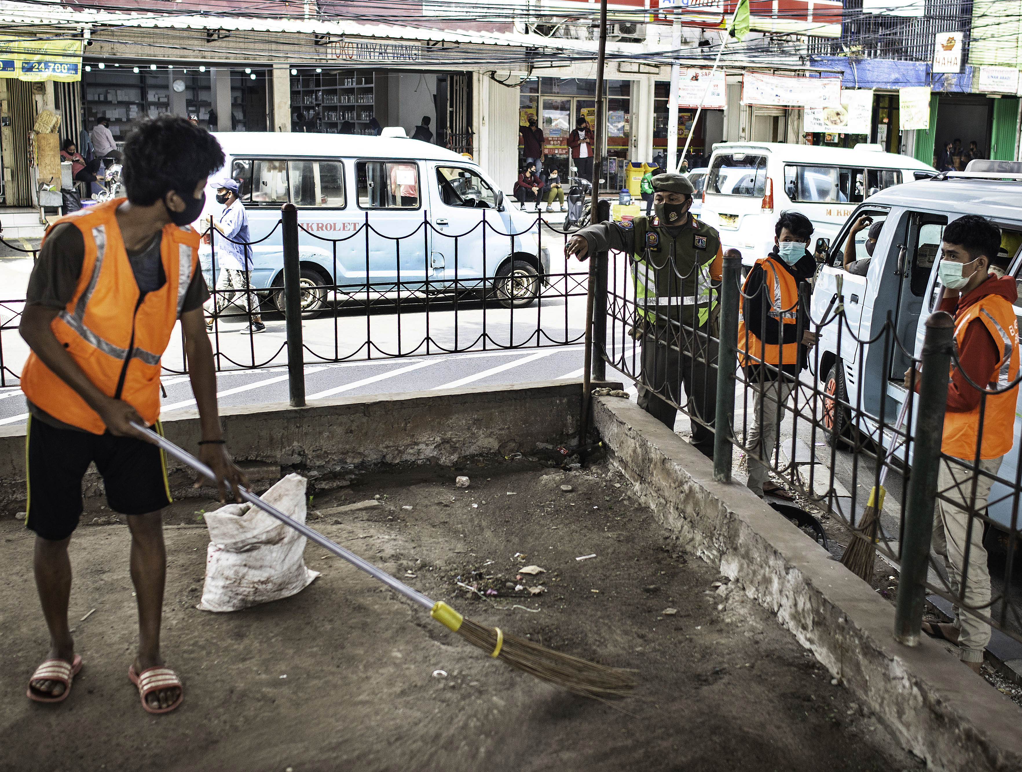 Warga yang melanggar aturan protokol kesehatan COVID-19 menyapu sampah saat terjaring Operasi Tertib Masker di kawasan Kampung Melayu