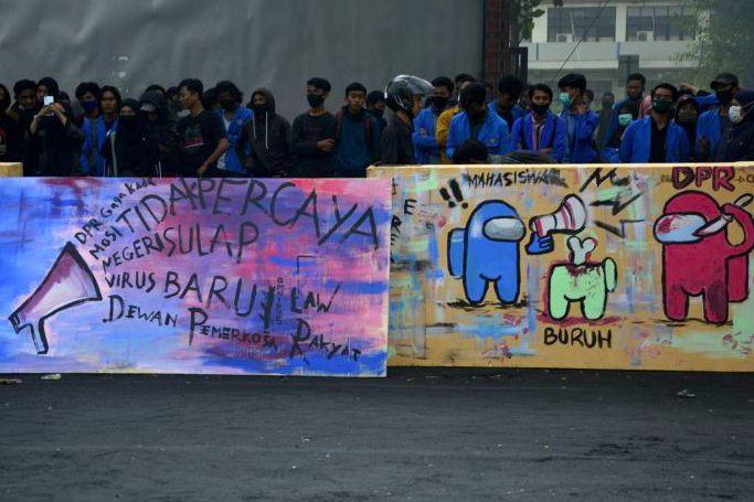 Sejumlah mahasiswa Universitas Muhammadiyah Makassar membuat mural saat berunjuk rasa di depan kampus Unismuh Makassar, Sulsel.  