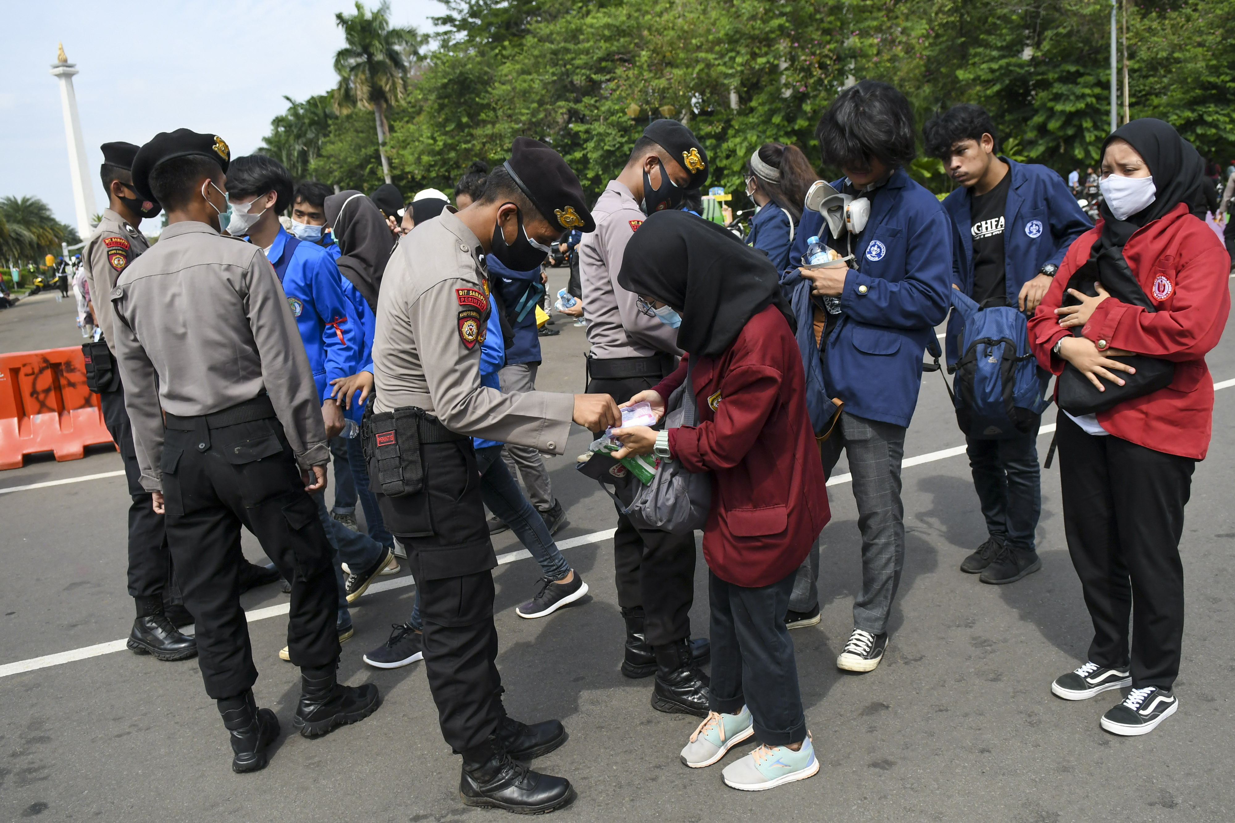 Polisi memeriksa barang bawaan peserta aksi unjuk rasa tolak UU Omnibus Law di kawasan Medan Merdeka Barat, Jakarta, Selasa (20/10).