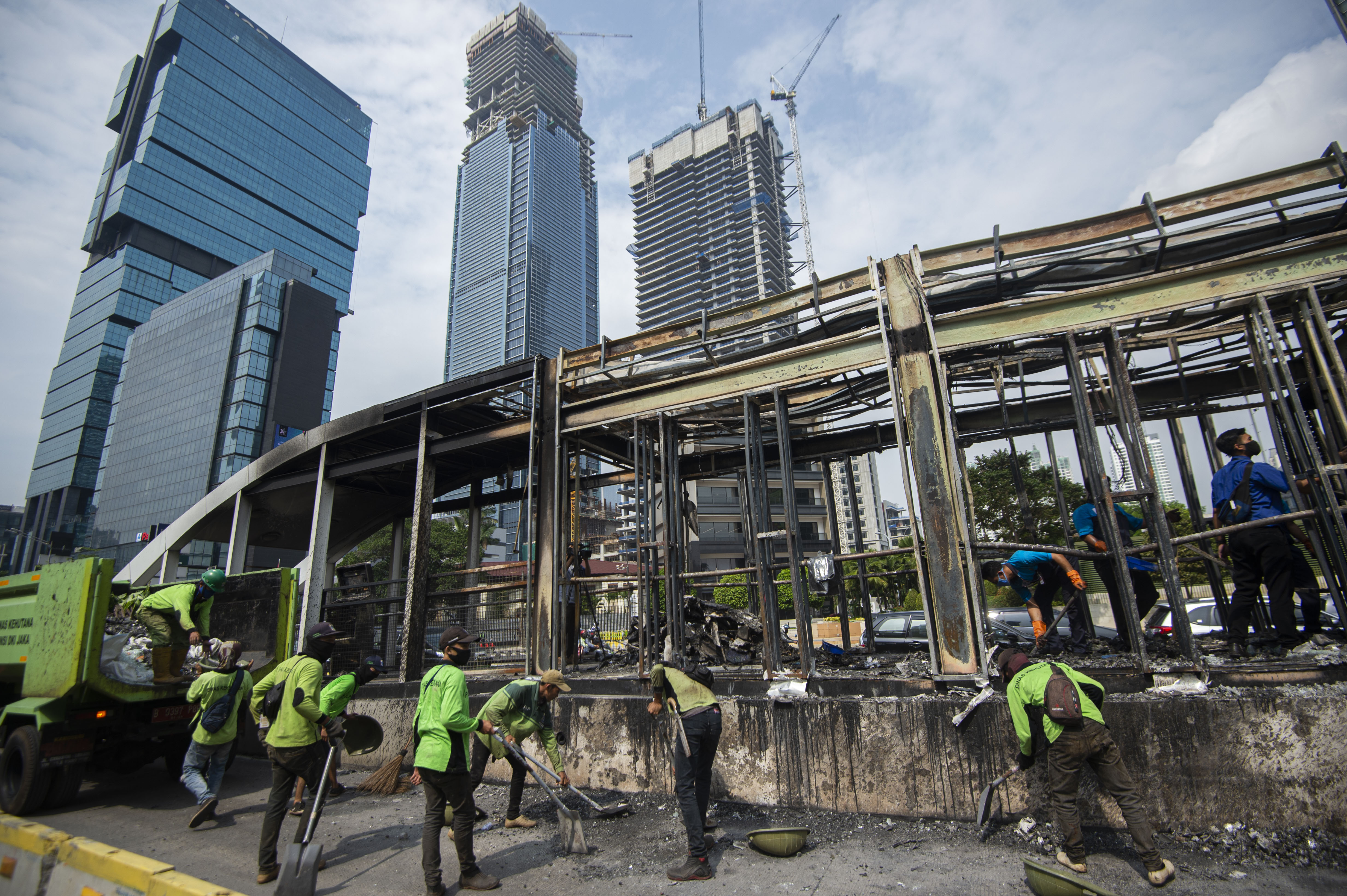 Sejumlah petugas membersihkan puing Halte Bus Transjakarta Tosari yang hangus di Jalan MH. Thamrin, Jakarta, Jumat (9/10).