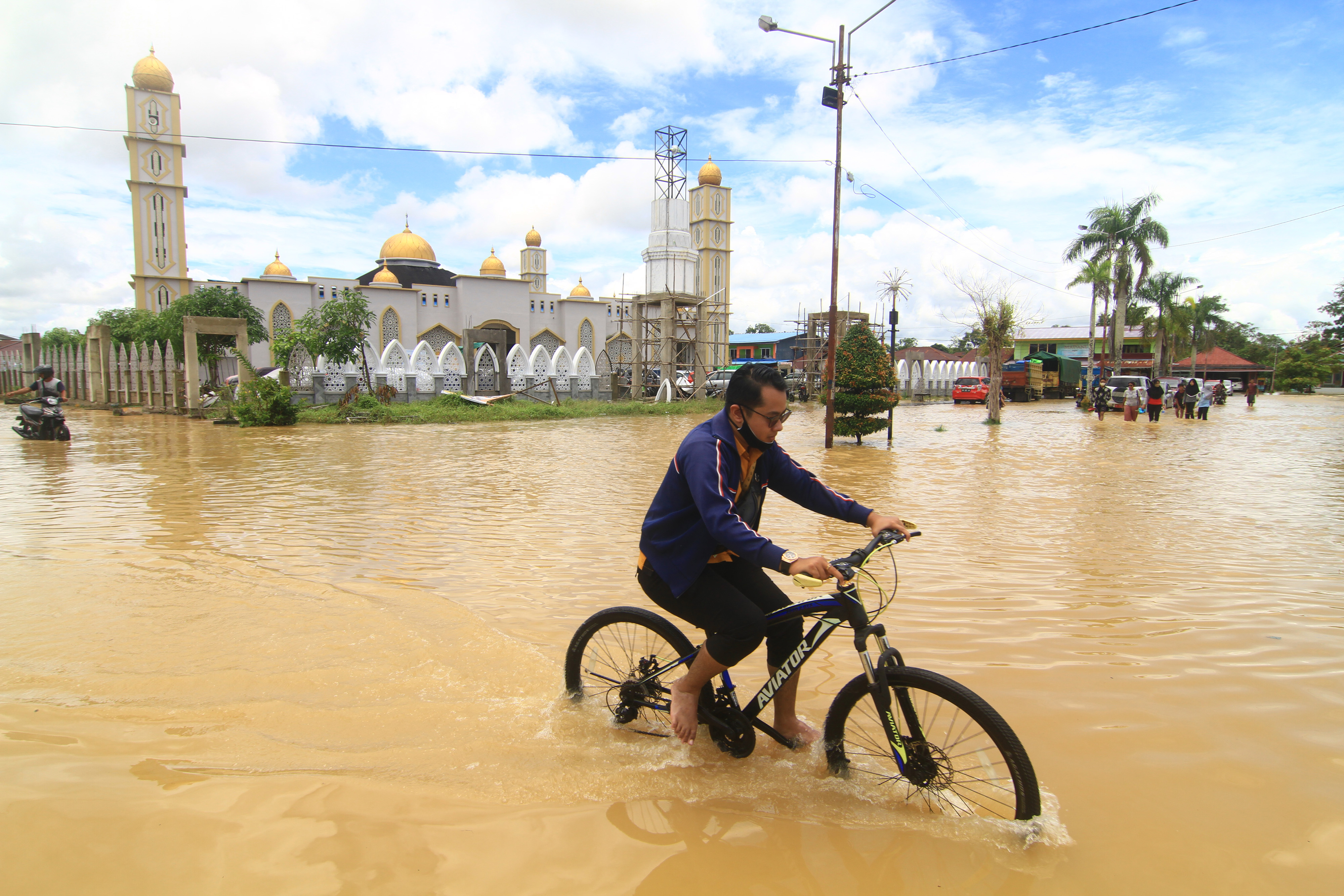 Pesepeda melintasi jalan yang terendam banjir di Kota Putussibau, Kalimantan Barat.
