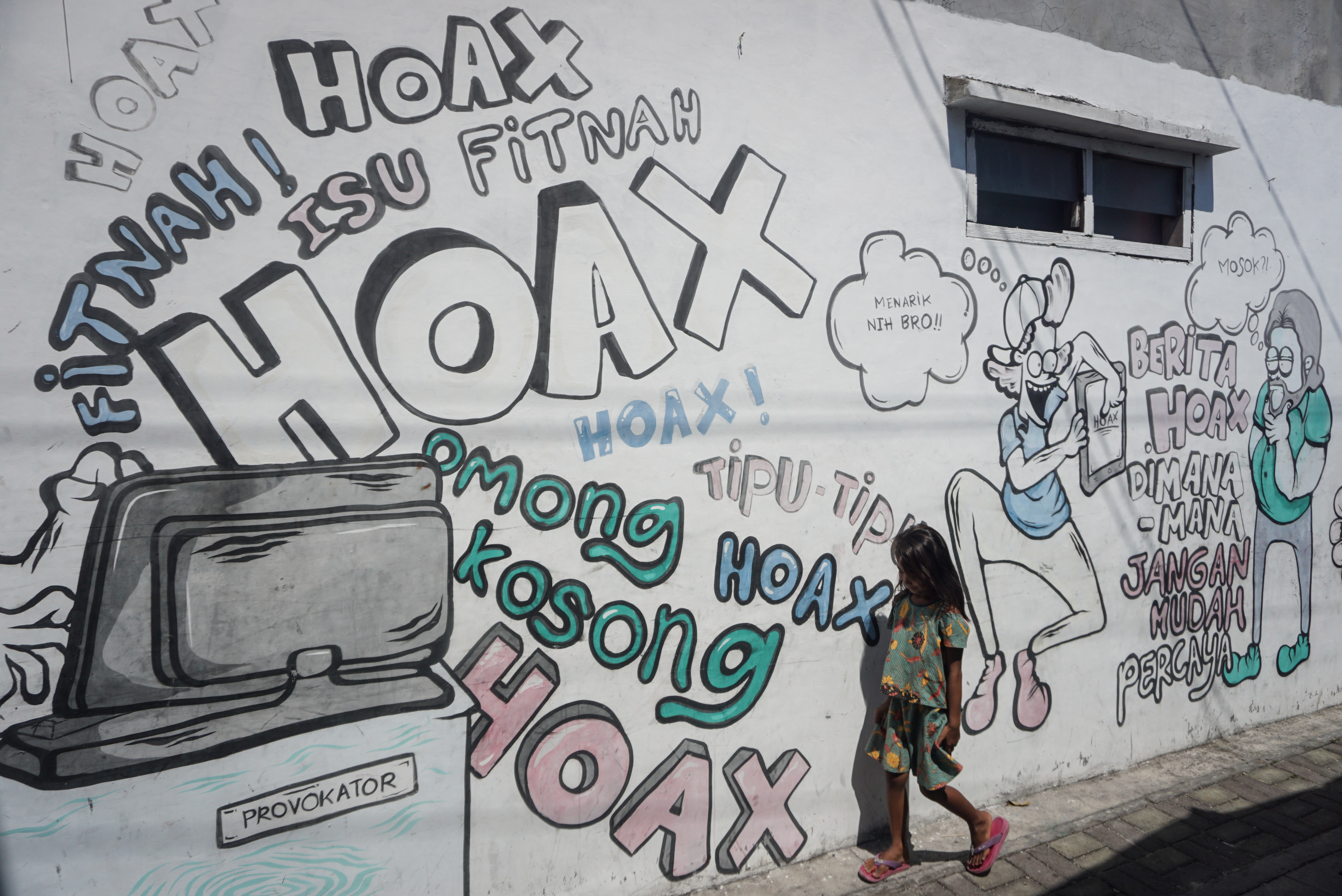  MURAL ANTI HOAX: Seorang anak melintas di depan mural bertema anti hoax (berita bohong) di Kampung Gandekan, Solo, Jawa Tengah.
