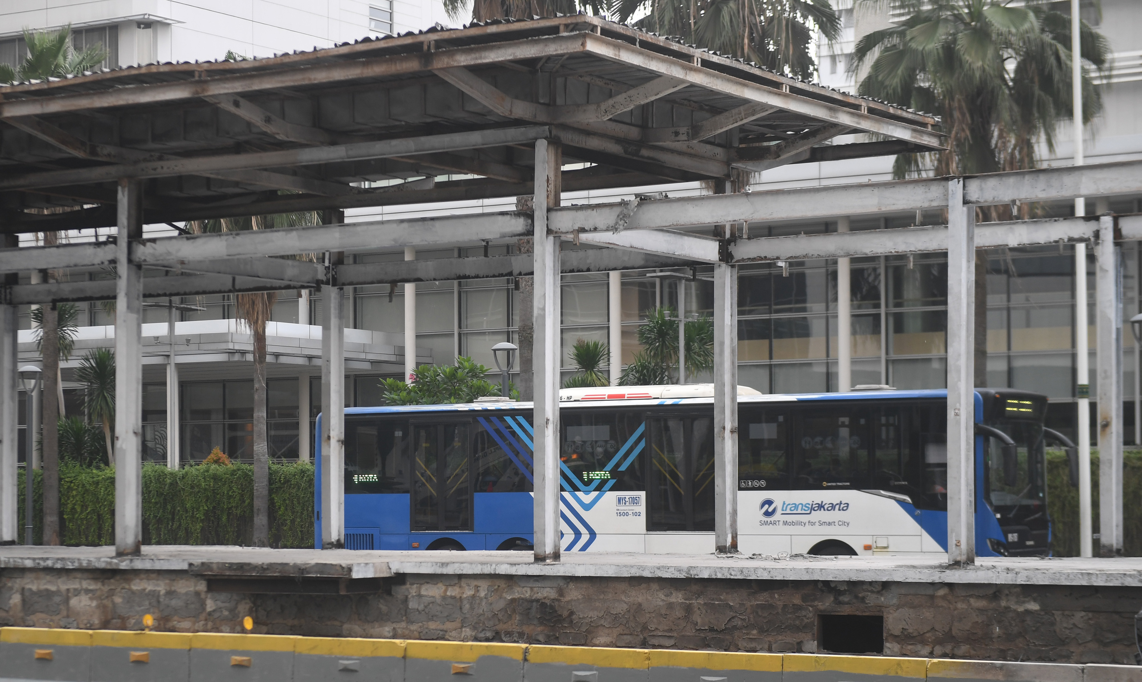 Bus Trans-Jakarta melintasi halte Bundaran HI yang hangus terbakar di Jakarta.