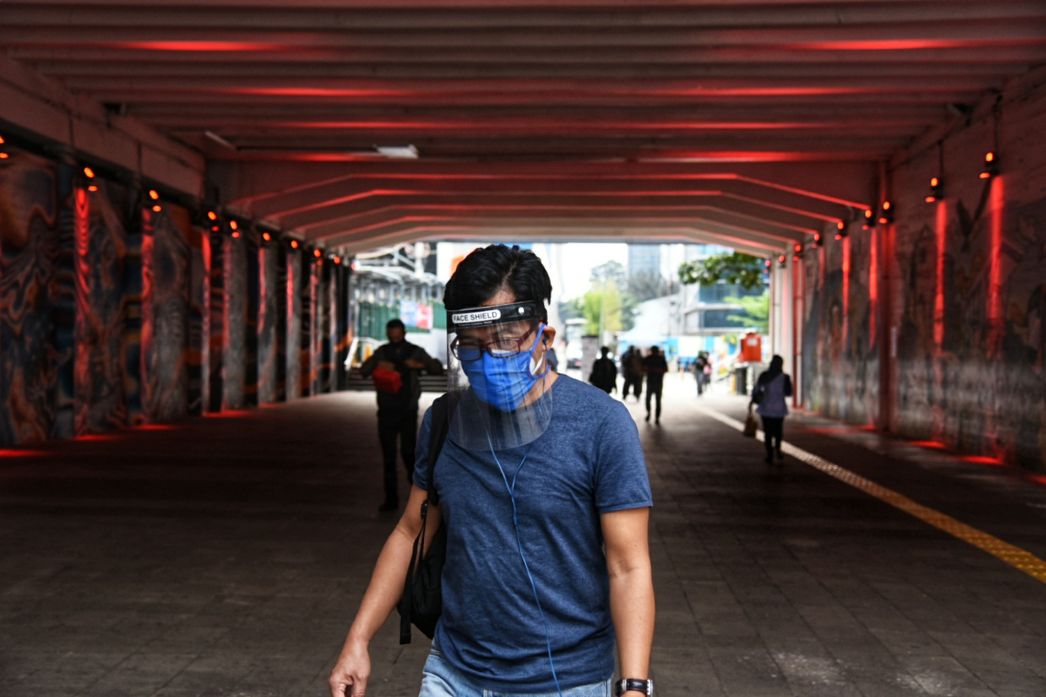 Warga mengenakan masker dan pelndung wajah melintas di Terowongan Kendal Jakarta Pusat. Terowongan menjadi penghubung transportasi publik.