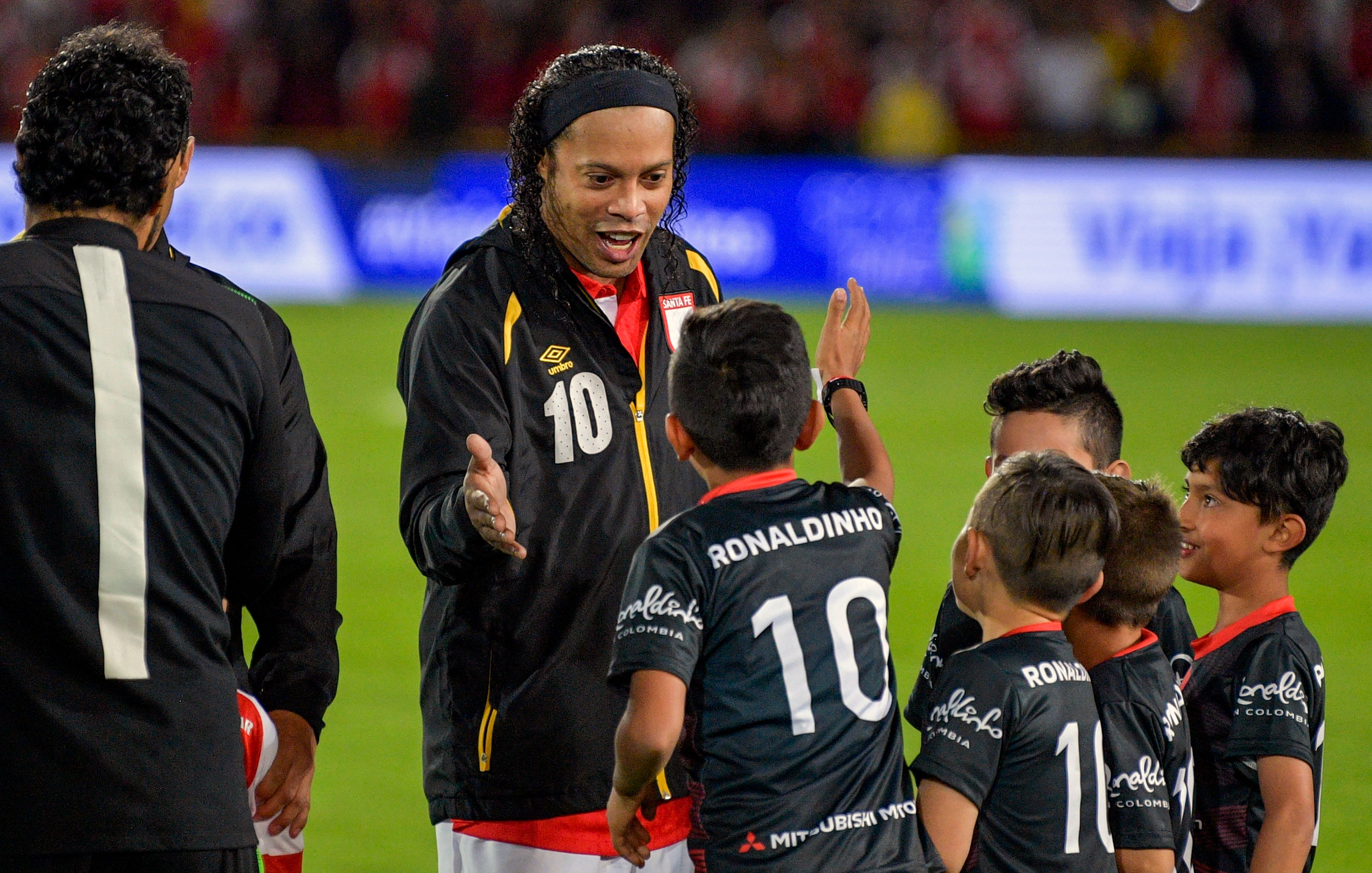 Legenda Brasil Ronaldinho saat menyalami anak-anak di pertandingan persahabatan.
