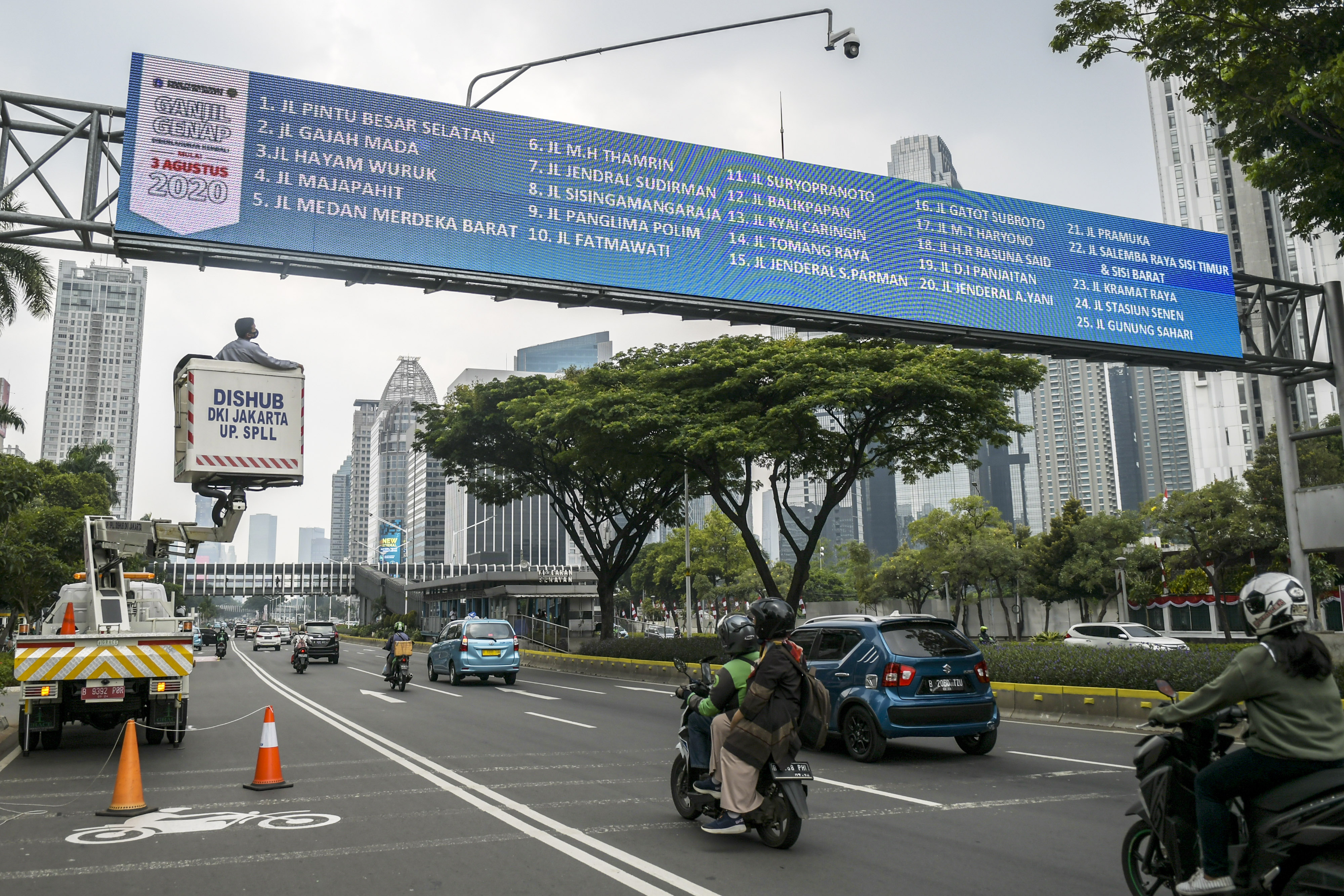 Petugas mengecek papan informasi mengenai kebijakan ganjil-genap di kawasan Jalan Sudirman, Jakarta.