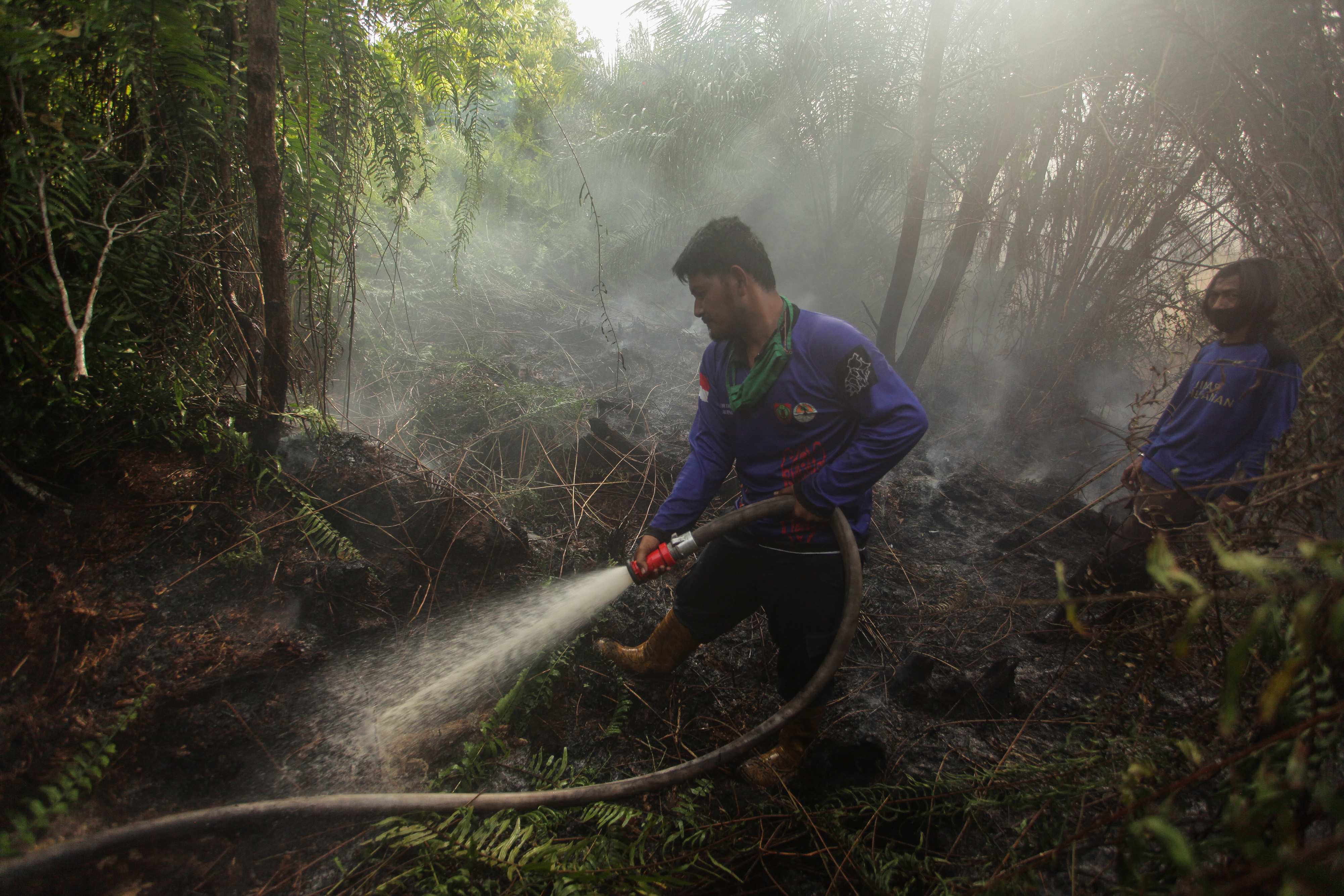Relawan pemadam kebakaran melakukan proses pembasahan lahan gambut yang terbakar di wilayah Jalan Tjilik Riwut, Palangkaraya