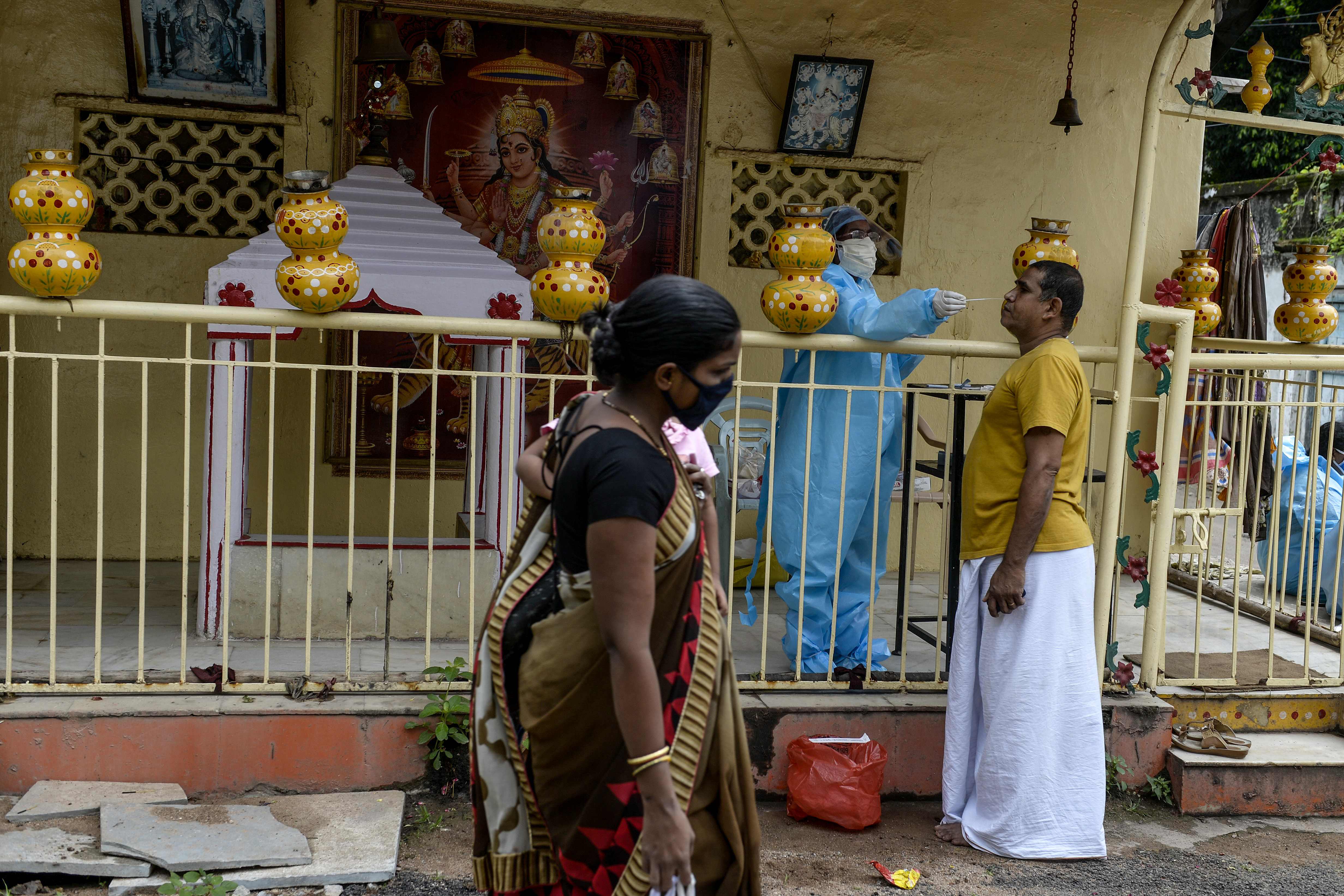 Petugas mengenakan APD melakukan swab test pada warga yang melintas di Hyderabad, India.