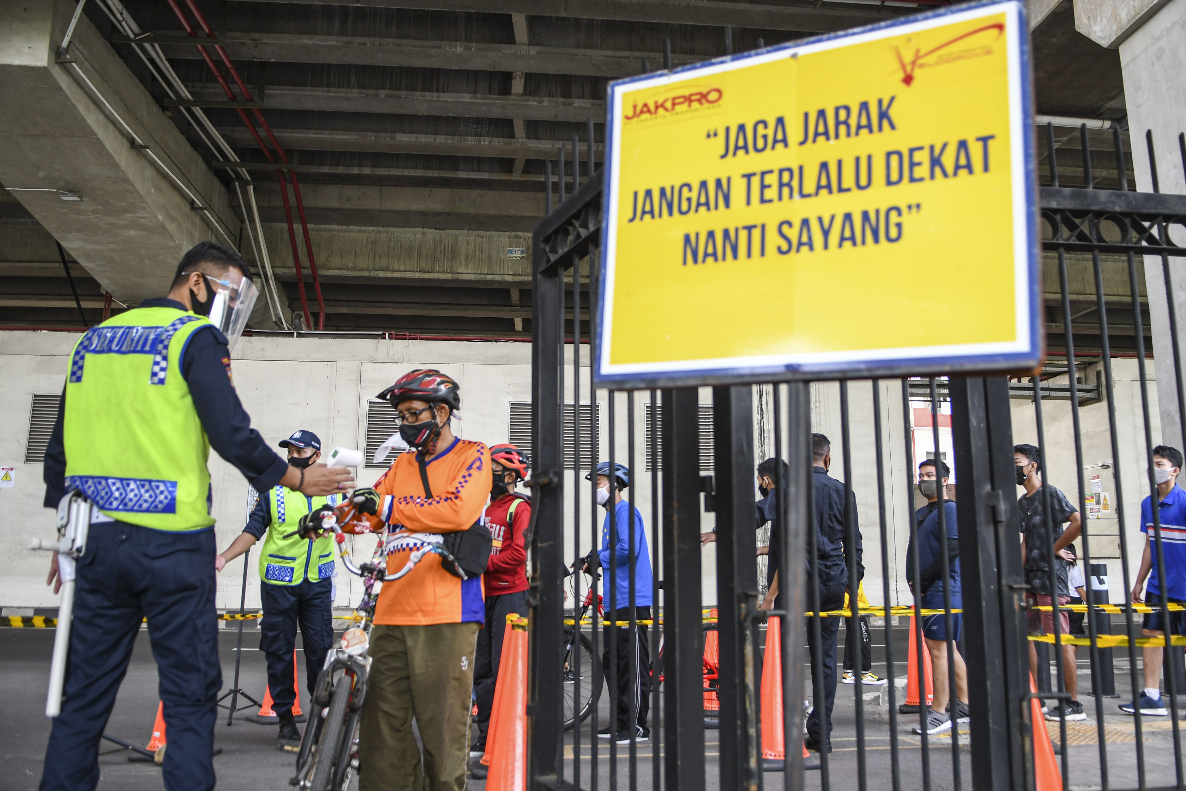 Petugas mengukur suhu tubuh dari warga yang akan berolahraga di Jakarta International Velodrome, Rawamangun, Jakarta.