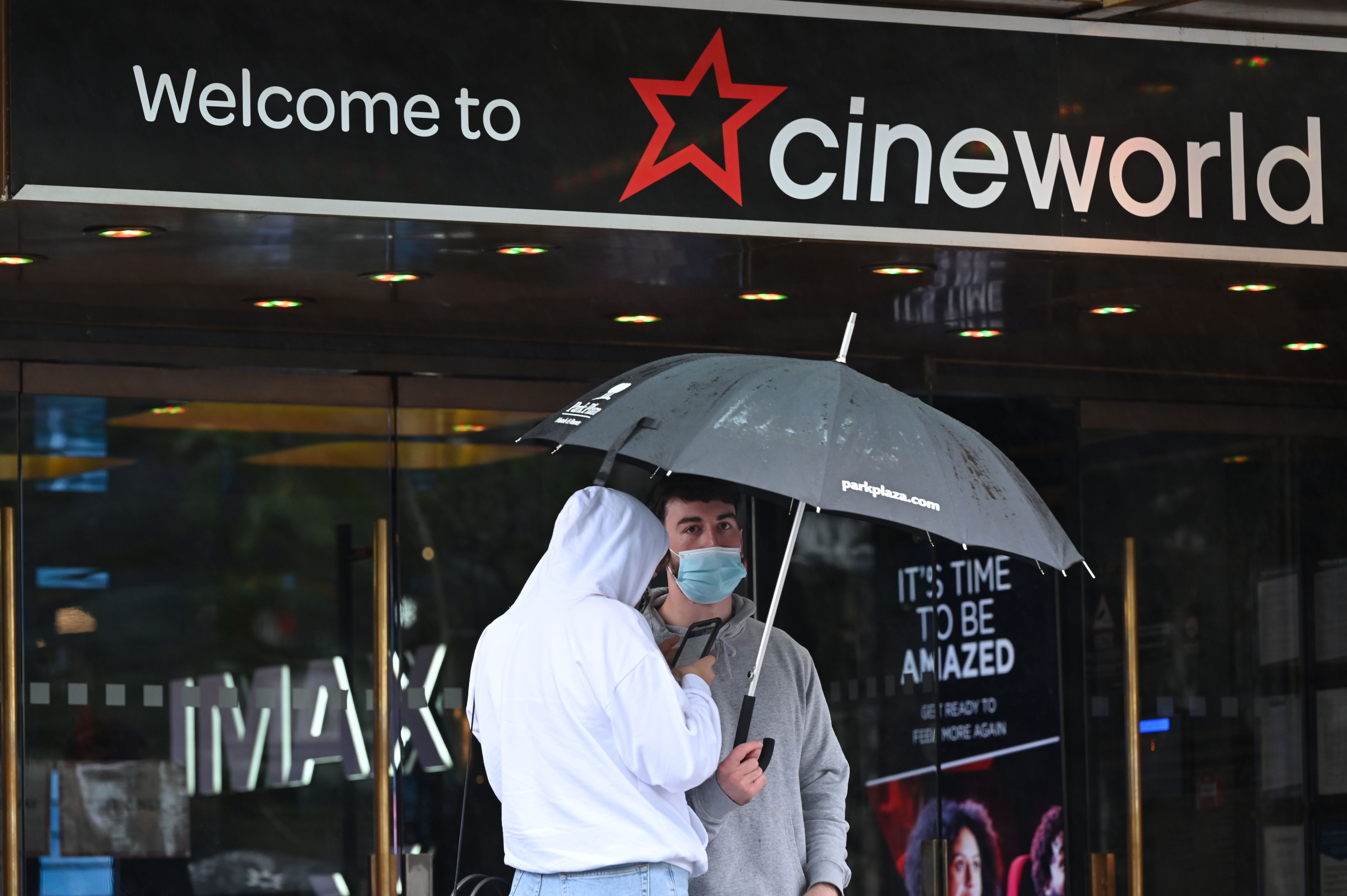 Warga London terlihat berteduh di depan bioskop Cineworld, yang segera tutup.