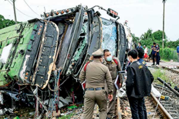 Petugas berwenang berada di lokasi bus yang terbalik akibat ditabrak kereta di dekat Stasiun Khlong Kwaeng Klan, Thailand