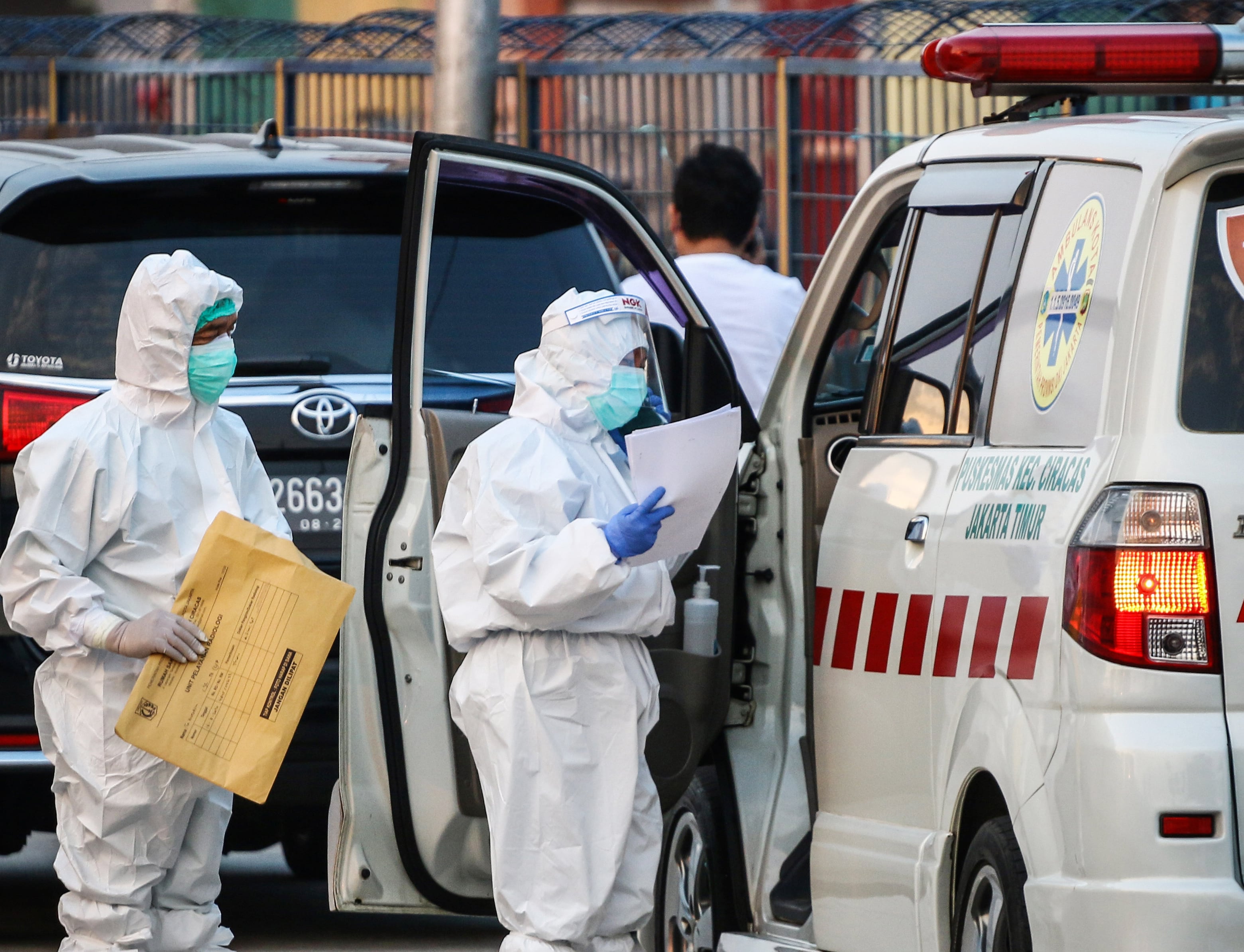 Petugas kesehatan memeriksa ambulnas yang membawa pasien Covid-19 OTG di wisma atlet Kemayoran