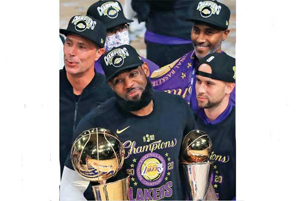 Pemain Los Angeles Lakers LeBron James berpose dengan dua trofi yang dia dapatkan setelah timnya menjuarai NBA