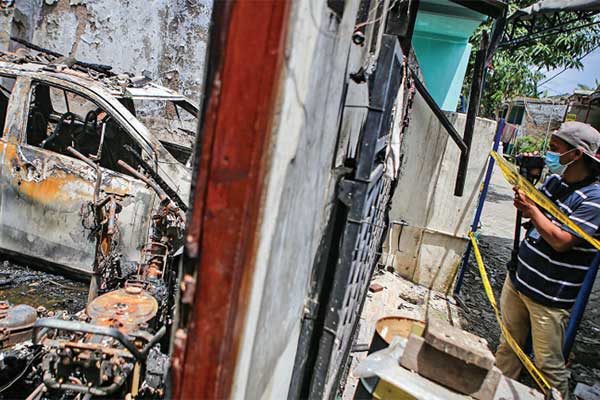 Seorang jurnalis mengambil gambar kondisi rumah yang terbakar di Legok, Kabupaten Tangerang, Banten, kemarin.