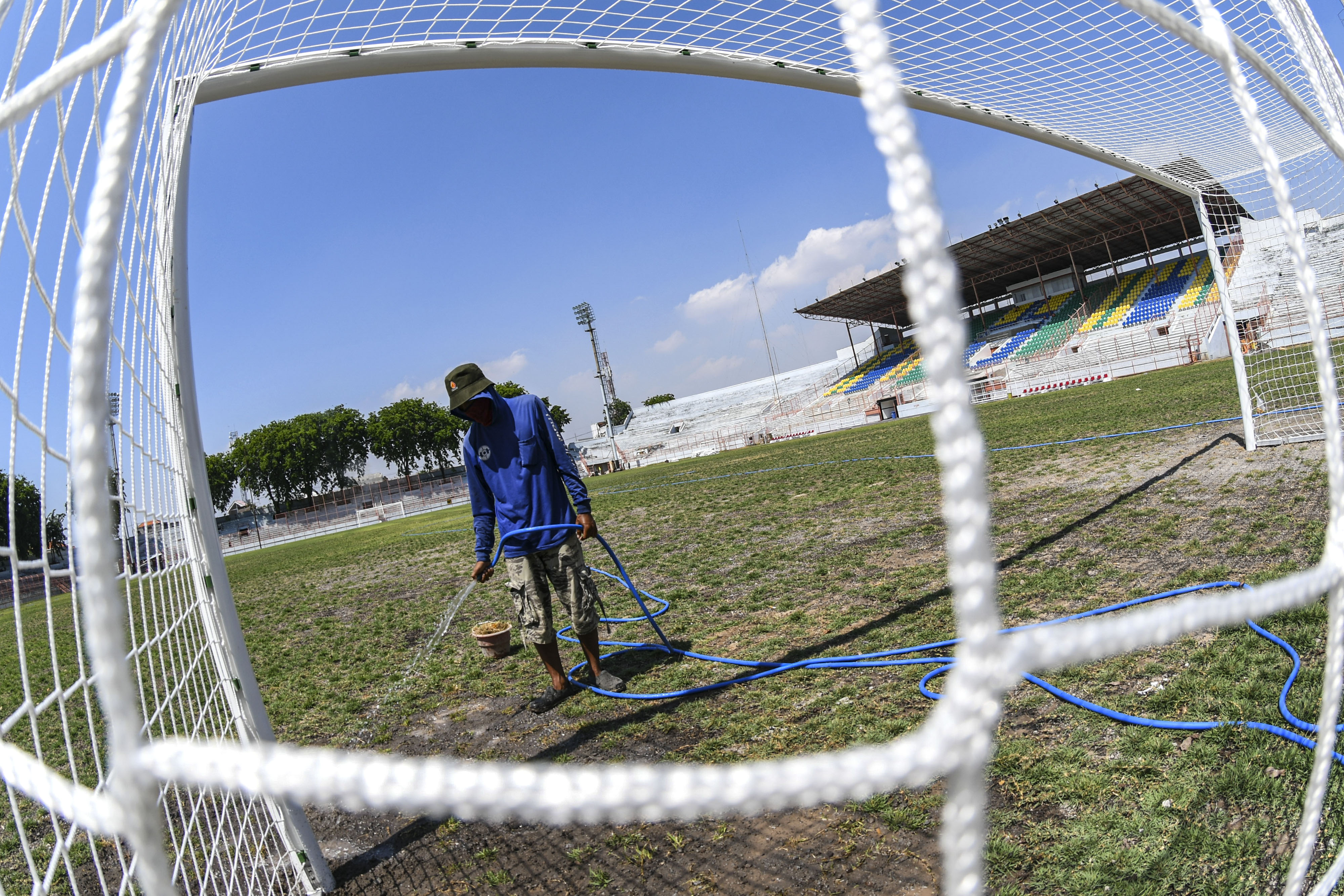 Pekerja menyiram rumput di lapangan Stadion Gelora 10 November di Surabaya, Jawa Timur.