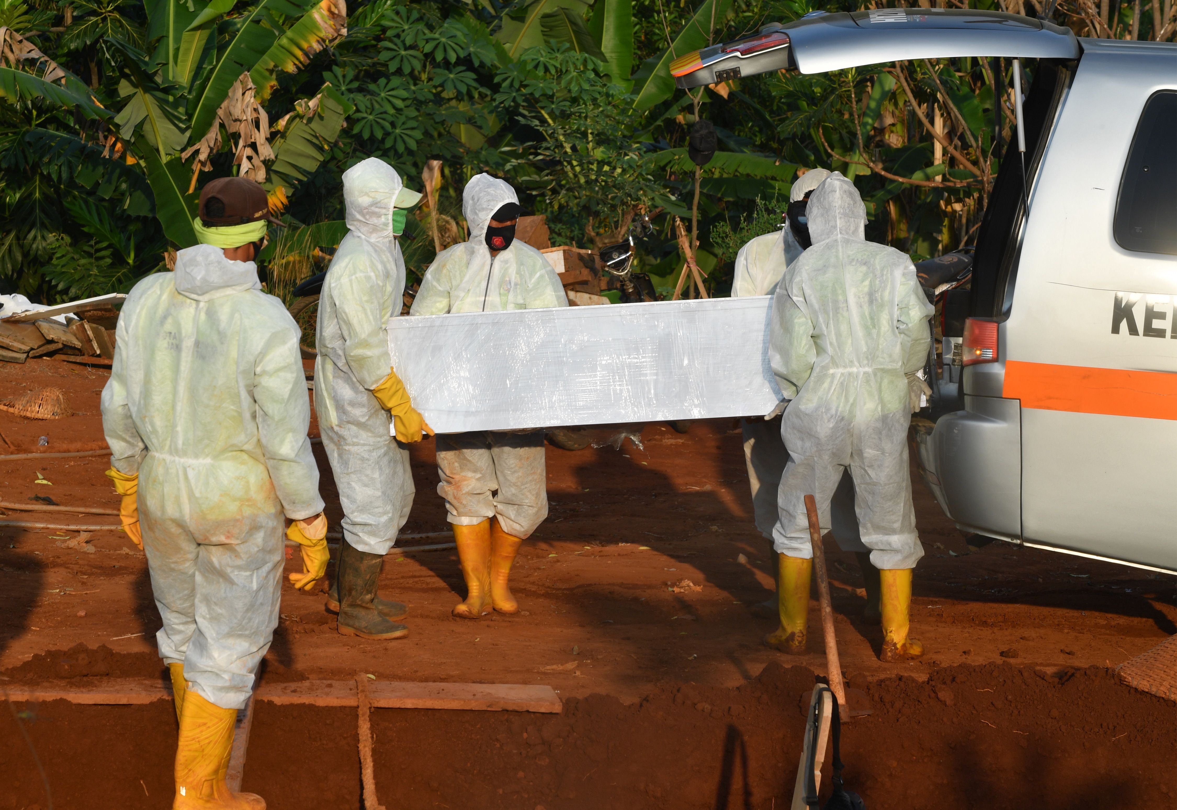 Petugas menurunkan peti jenazah pasien covid-19 di TPU Pondok Ranggon, Jakarta.