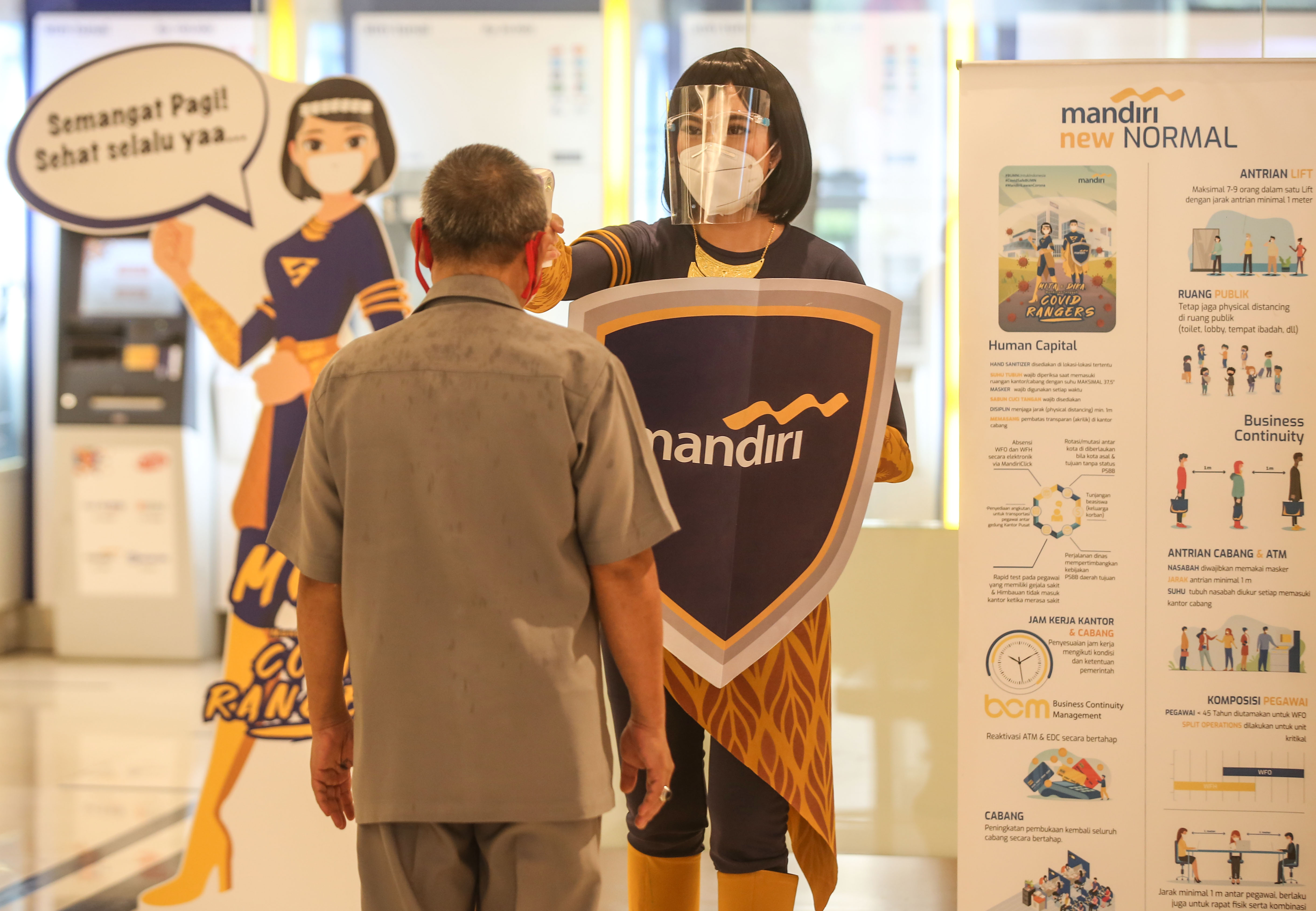 Nasabah diperiksa suhu tubuh sebelum memasuki cabang Bank Mandiri