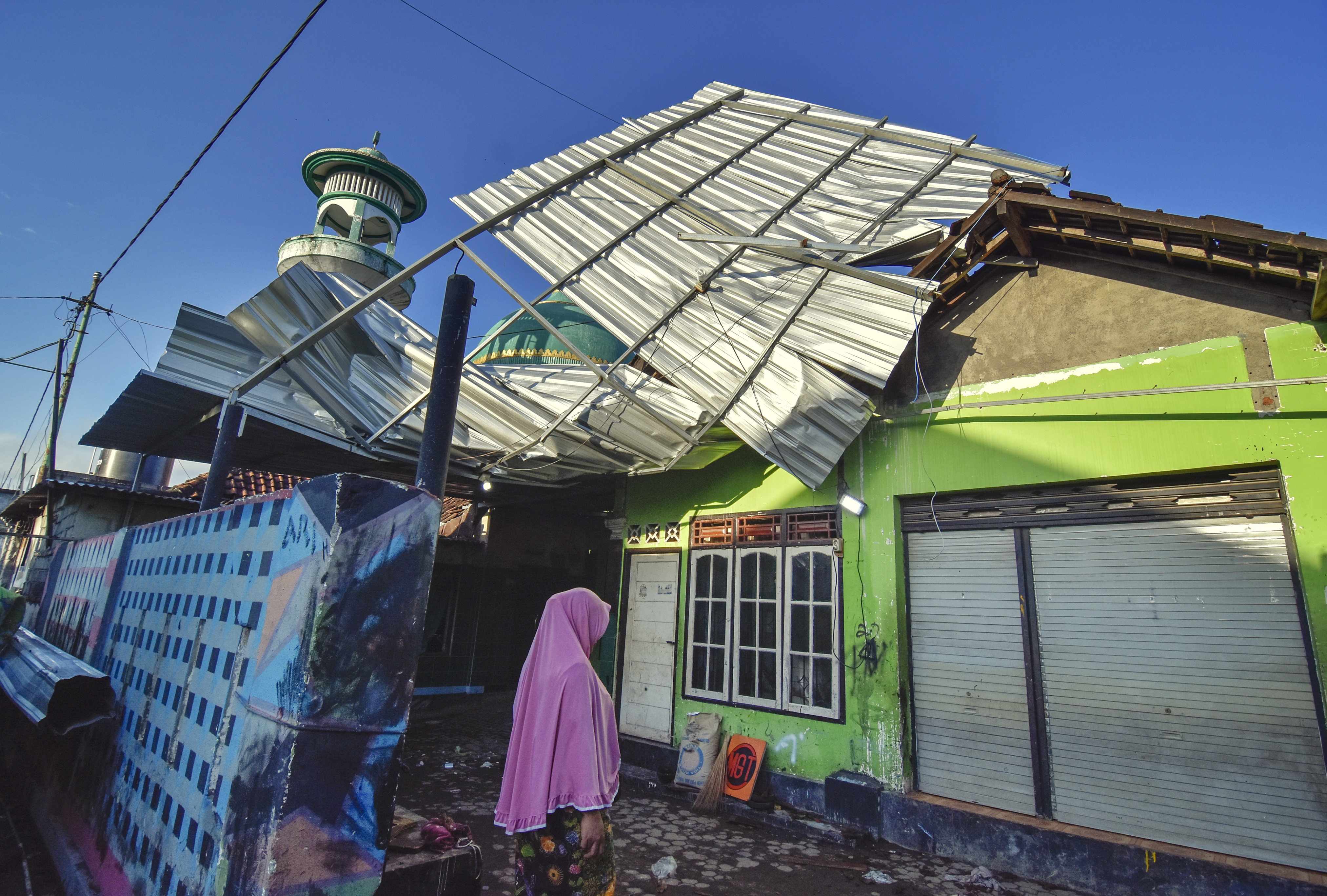 Seorang perempuan berada di rumah yang atapnya rusak akibat diterjang angin puting beliung di Desa Badrain, Lombok Barat, kemarin.