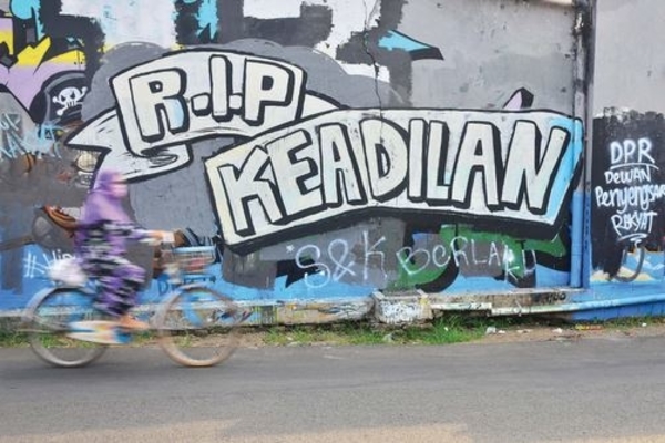Ilustrasi -- Warga melintas di depan mural bertuliskan ‘RIP Keadilan’, di Jalan Veteran, Kota, Kudus, Jawa Tengah, kemarin.