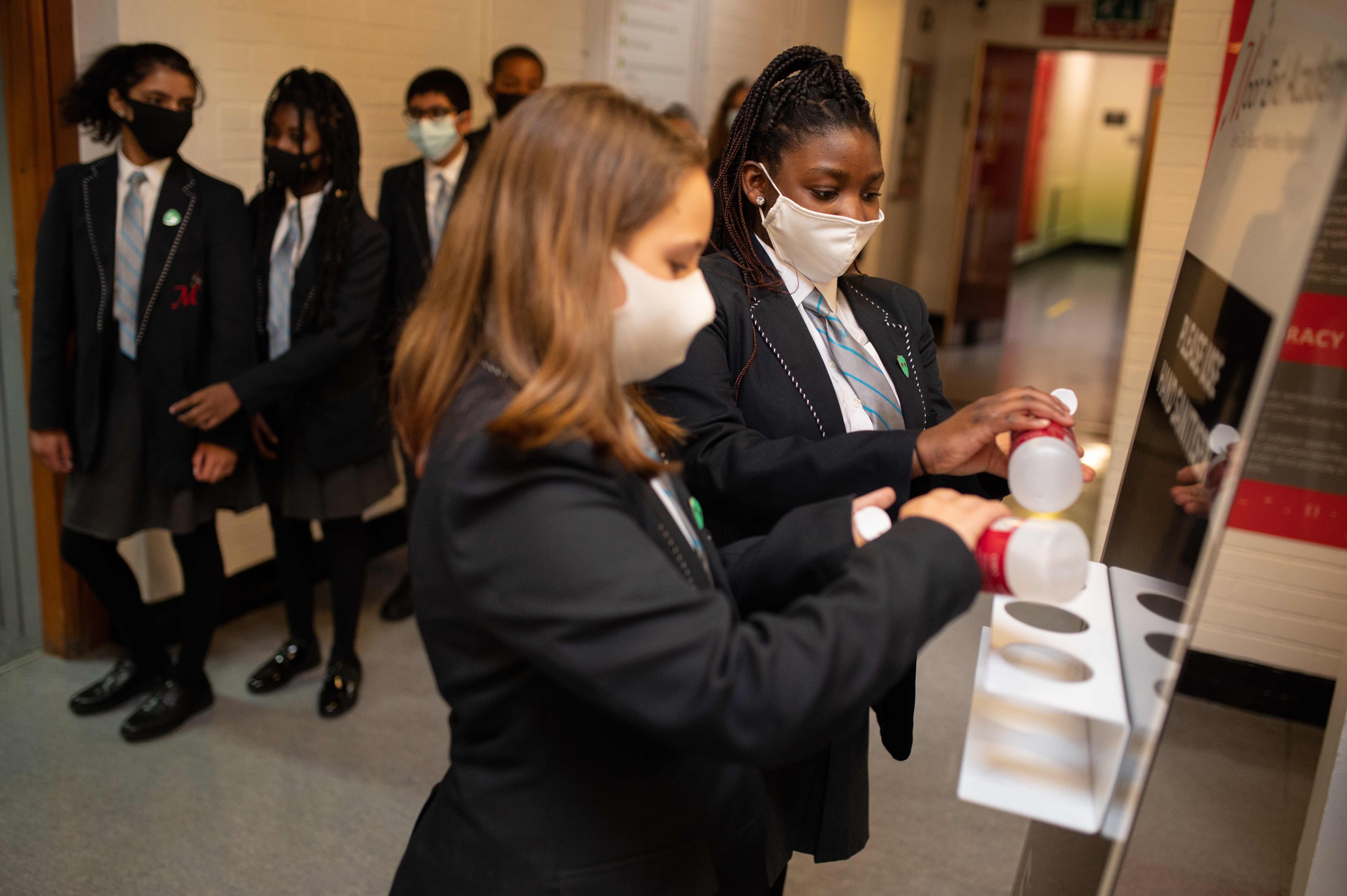 Ilustrasi--Anak-anak membersihkan tangan mereka menggunakan hand sanitiser di sebuah sekolah di Inggris.
