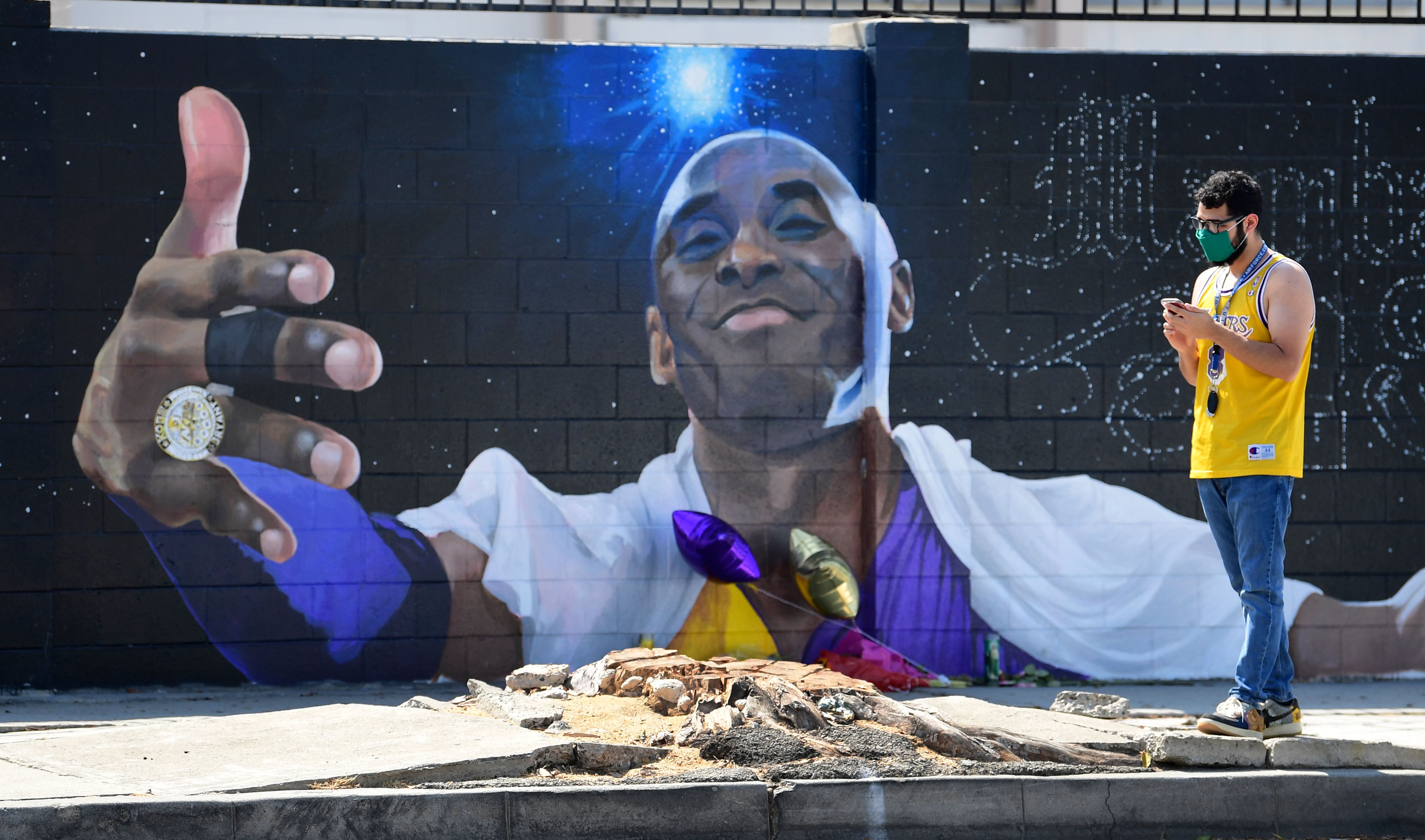Penggemar LA Lakers melewati mural Kobe Bryant di California, Amerika Serikat pada Senin (24/8).