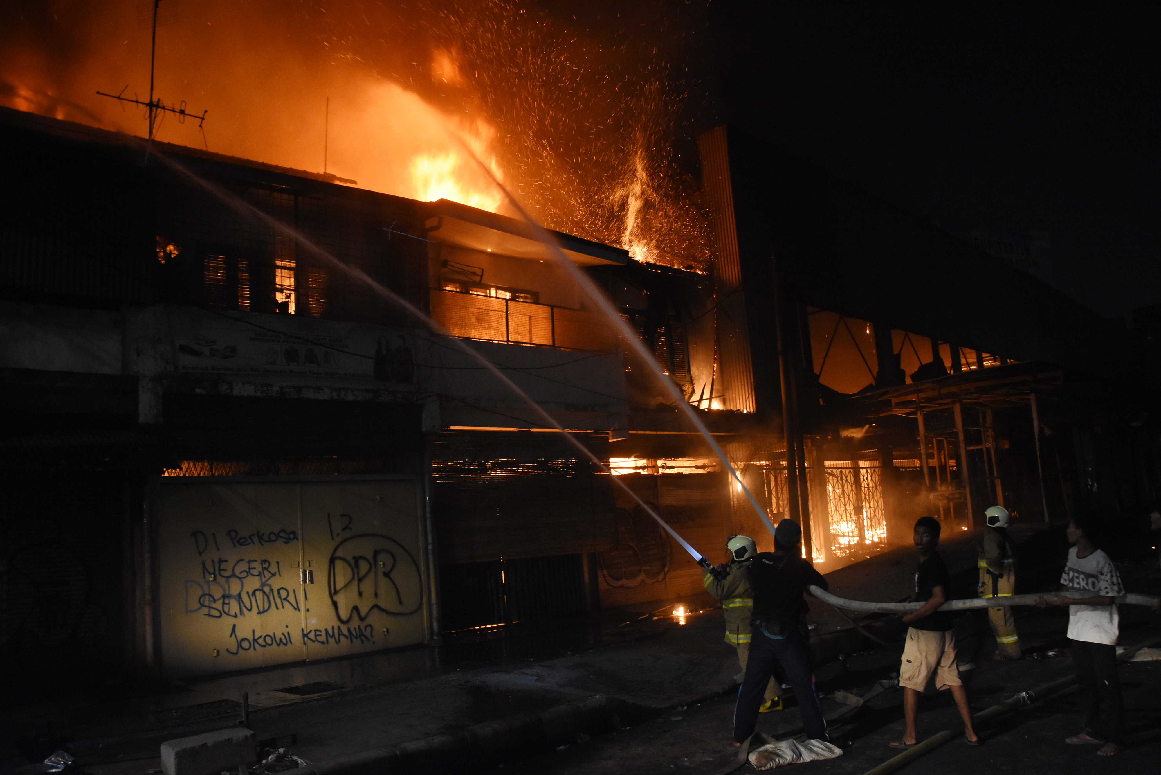 Petugas Pemadam Kebakaran dibantu warga memadamkan api yang menghanguskan bangunan di kawasan Senen, Jakarta, Kamis (8/10/2020) malam