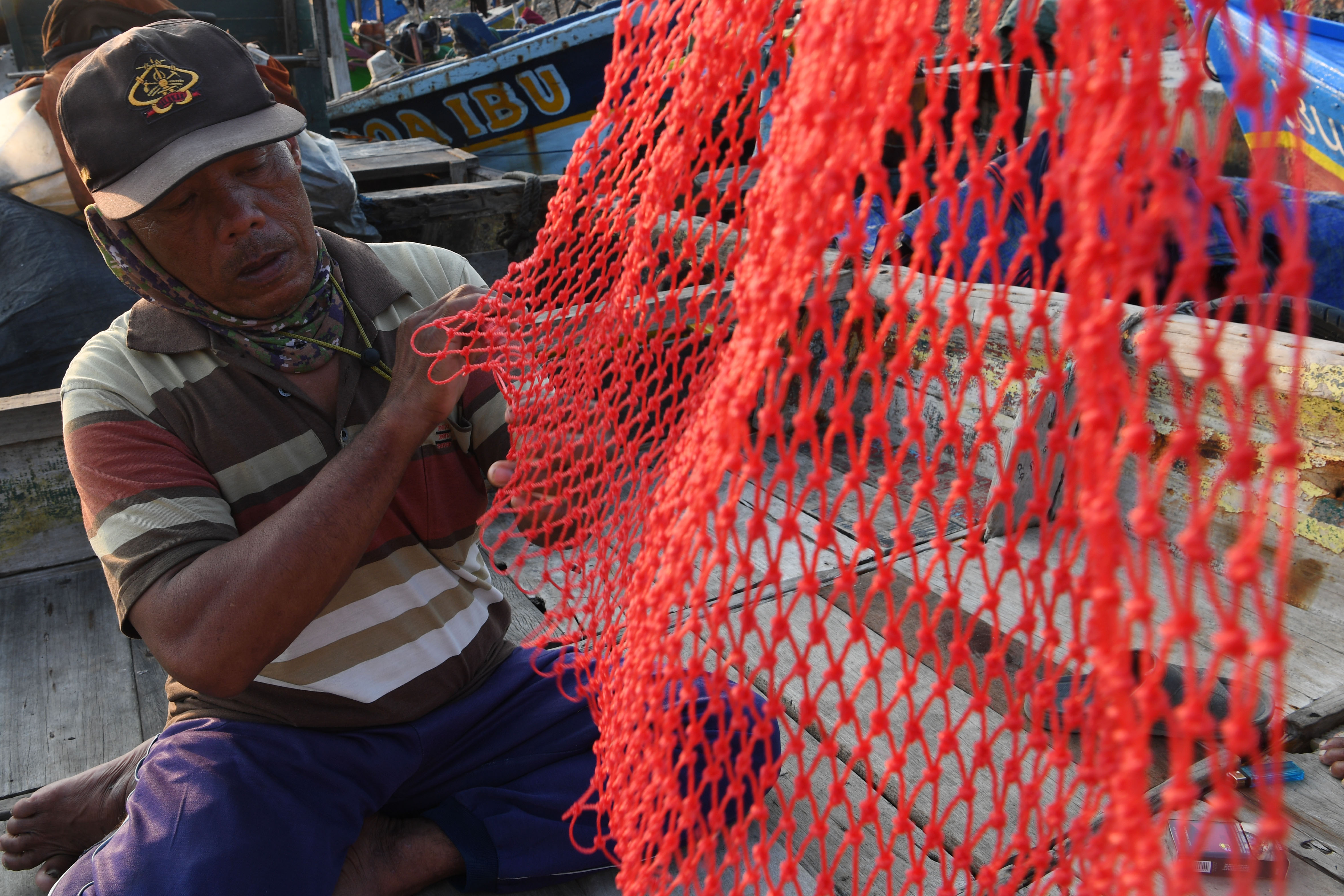 Nelayan memperbaiki jaring untuk menangkap ikan