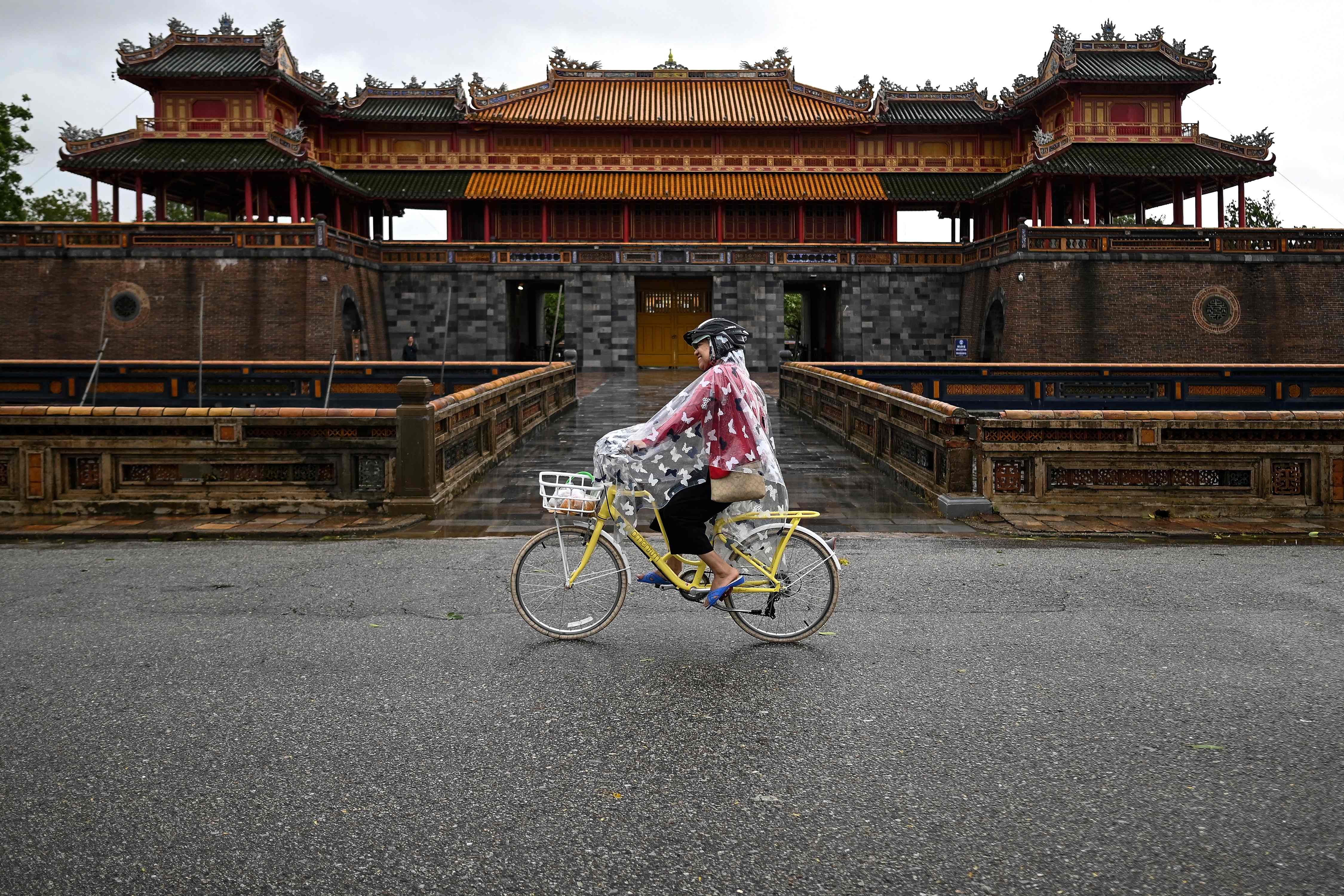 Pengendara sepeda menerobos hujan di  the Hue Imperial Palace di Kota Vietnam, hujan menyebabkan longsor disejumlah tempat di san 