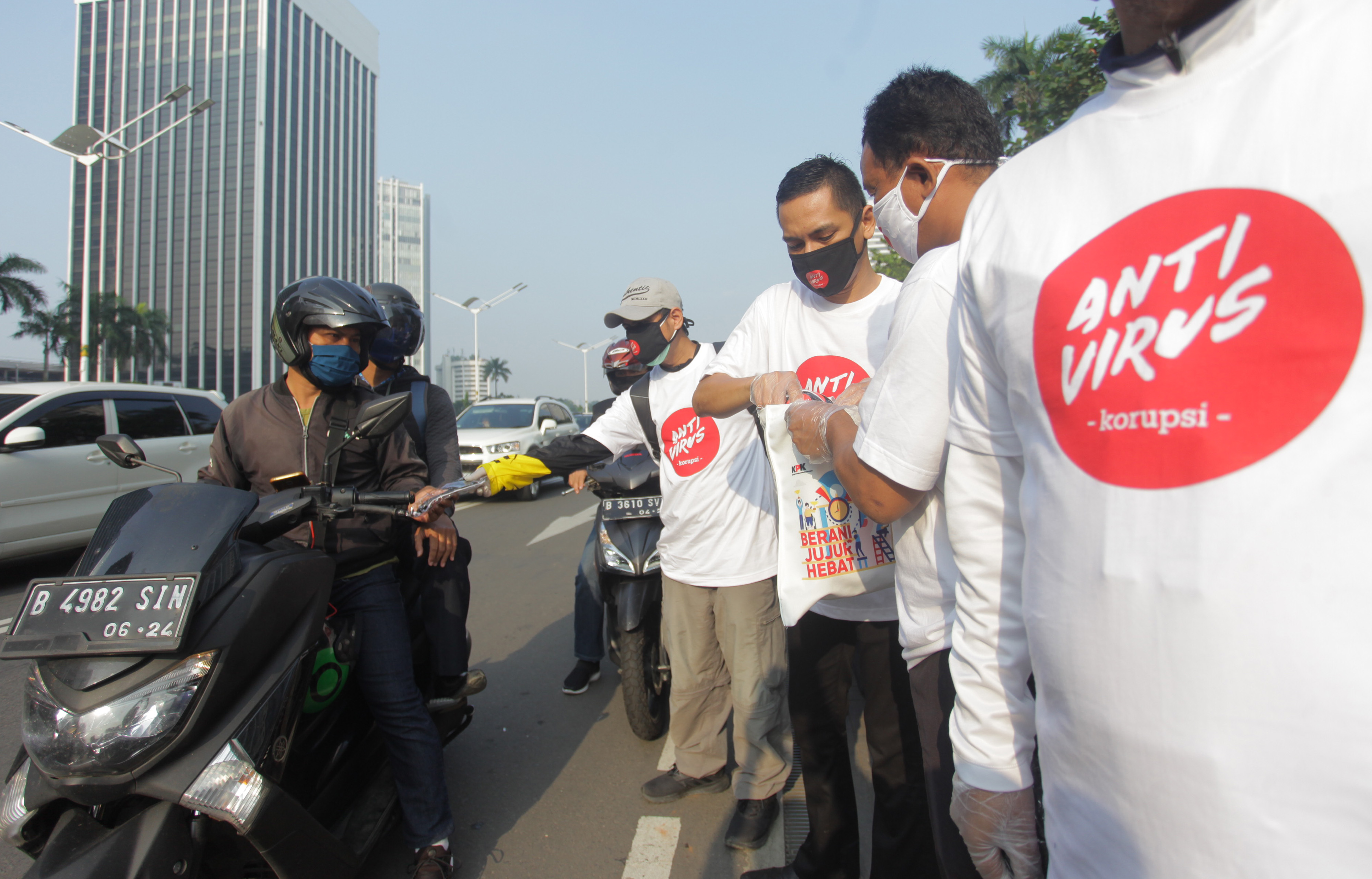 Sejumlah pegawai KPK membagikan masker bertuliskan Antivirus Korupsi ke pengendara yang melintas di Jalan Sudirman, Jakarta.
