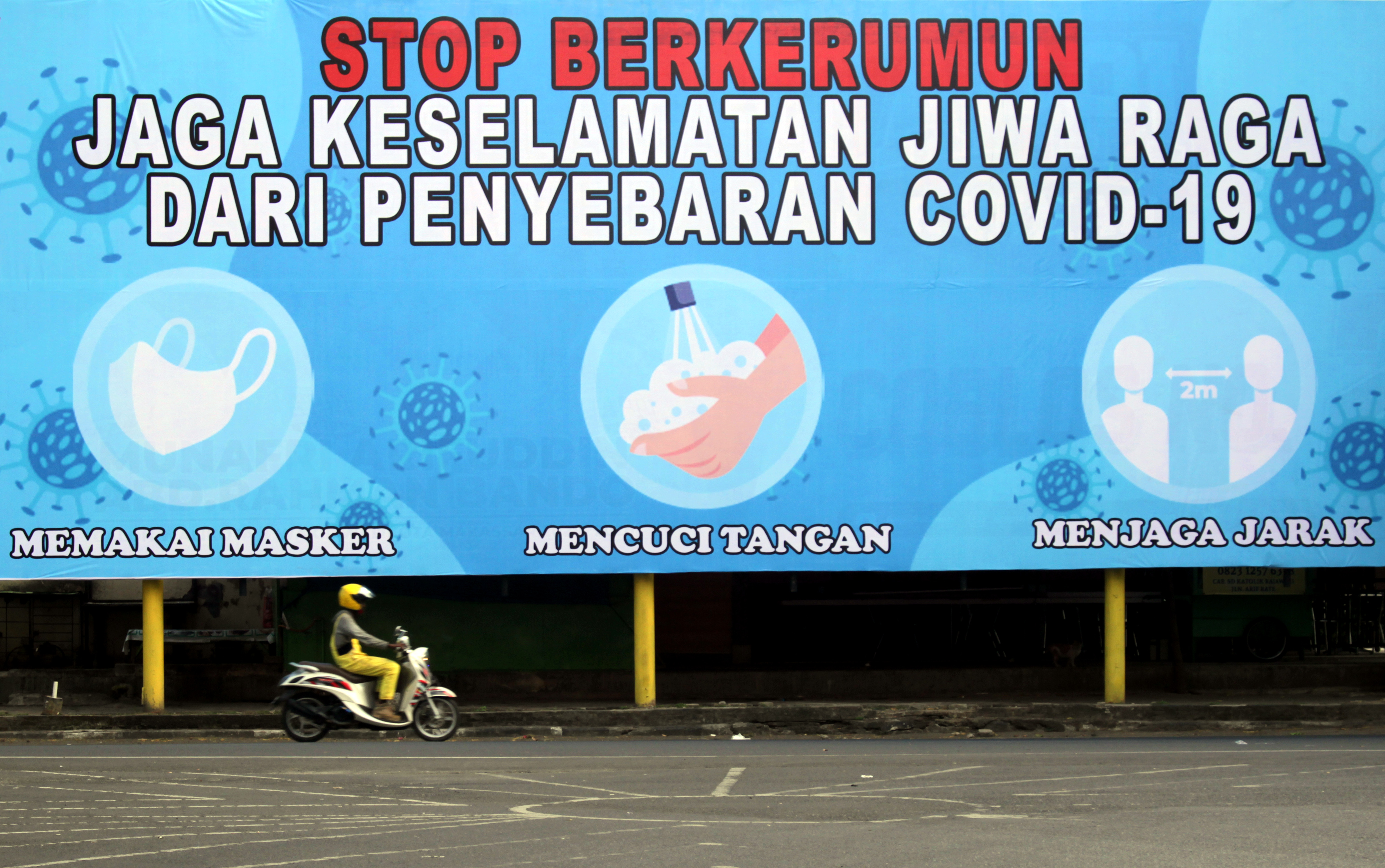 Pengendara melintas di depan baliho edukasi penerapan protokol kesehatan di Makassar, Sulawesi Selatan, Rabu (14/10/2020). 