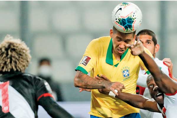Penyerang Brasil Roberto Firmino (tengah) memenangi duel udara dengan pemain Peru Luis Advincula. 