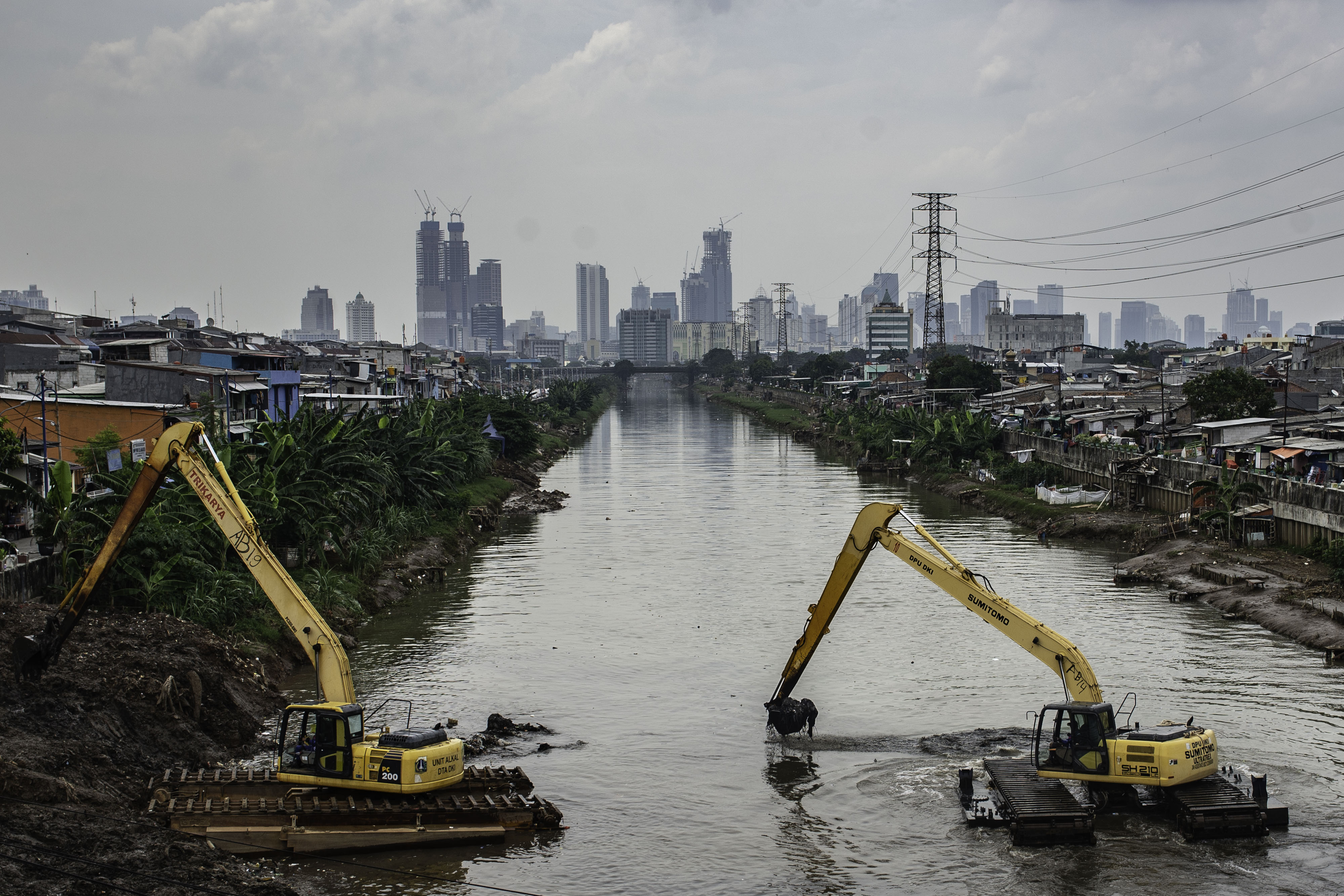 Petugas menggunakan alat berat untuk mengeruk sampah dan lumpur di Banjir Kanal Barat, Jakarta.