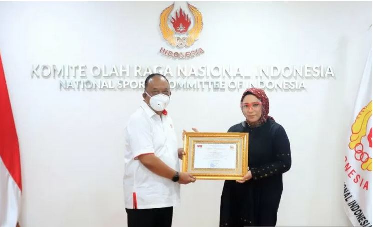 Ketua Umum KONI Pusat Marciano Norman (kiri) memberikan penghargaan kepada Alm Melky Goeslaw yang diwakili oleh putrinya, Melly Goeslaw.