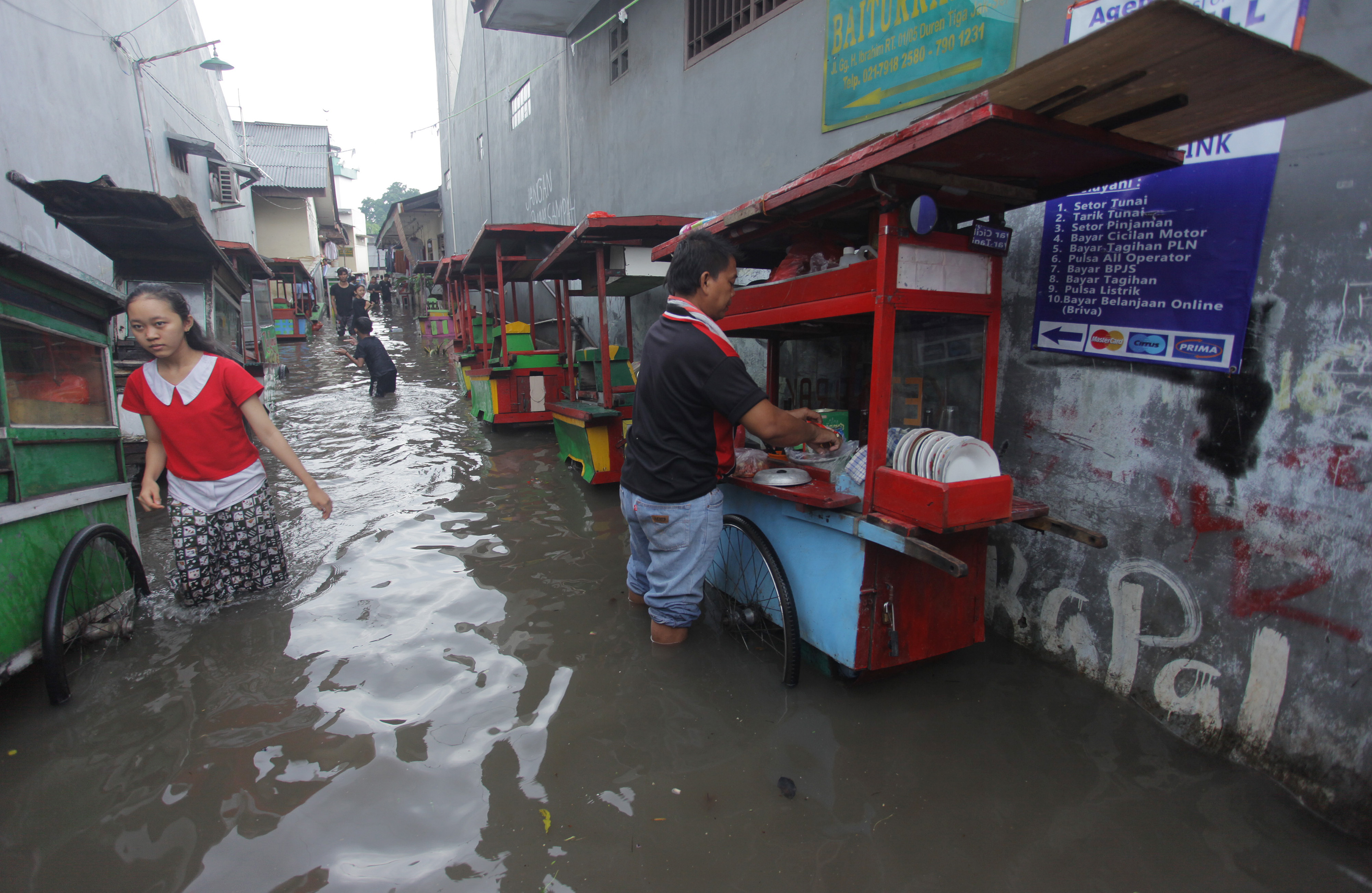 BANJIR DI KEMANG UTARA: Warga berjalan melewati banjir yang melanda permukiman di Kemang Utara, Jakarta, Minggu (8/11/2020).